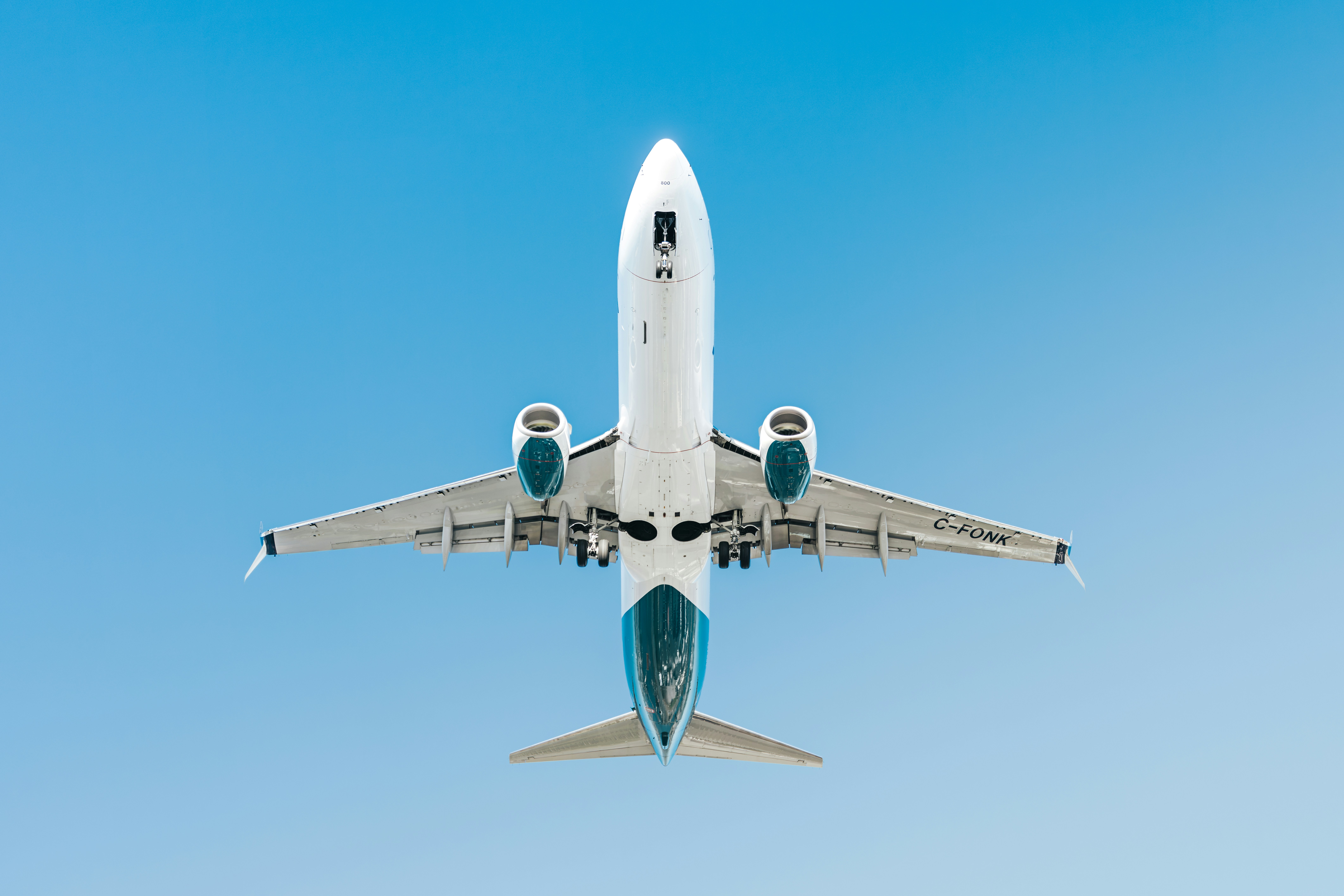 An airplane flying directly overhead against a clear blue sky.