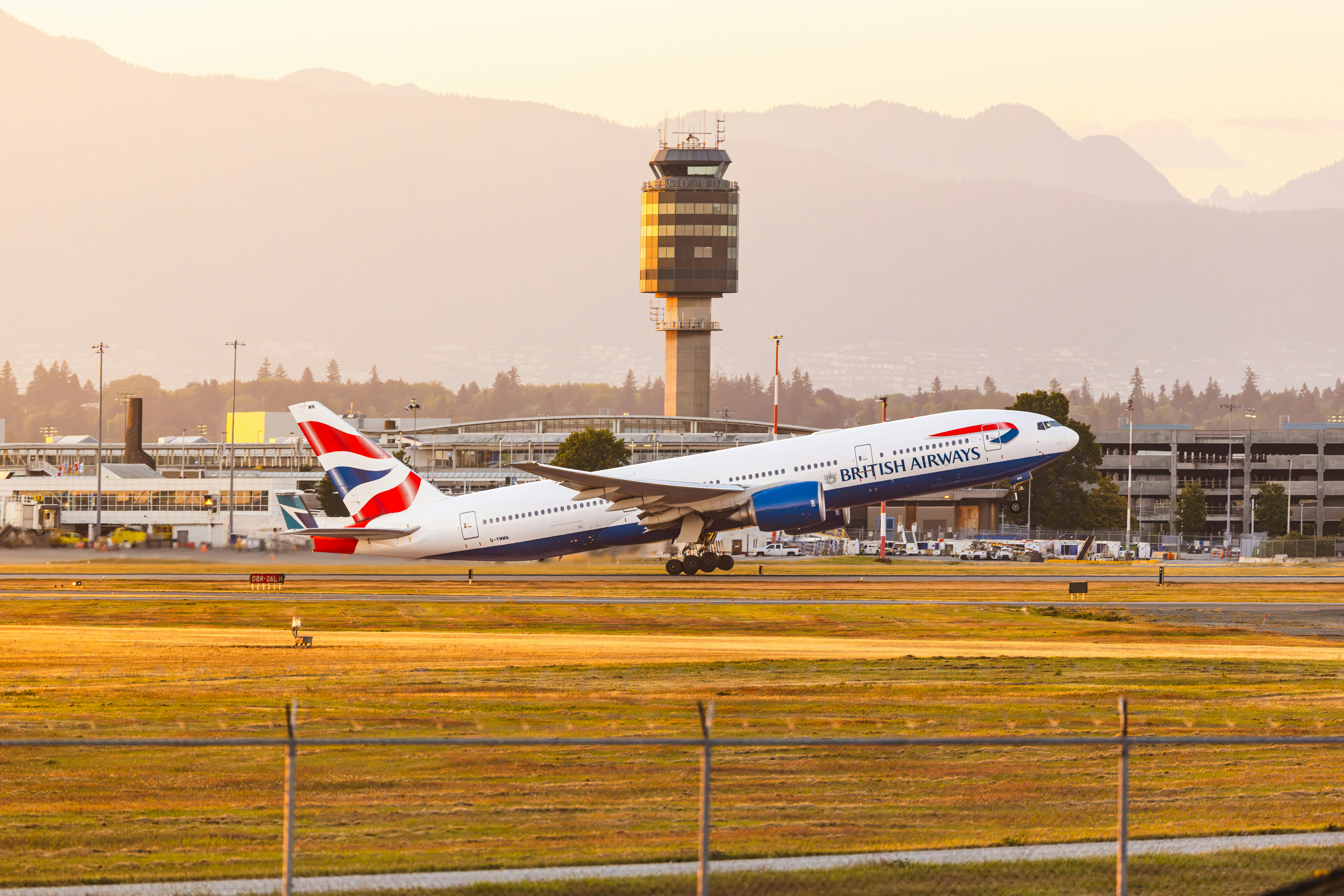 British airways airplane taking off from an airport at sunset.