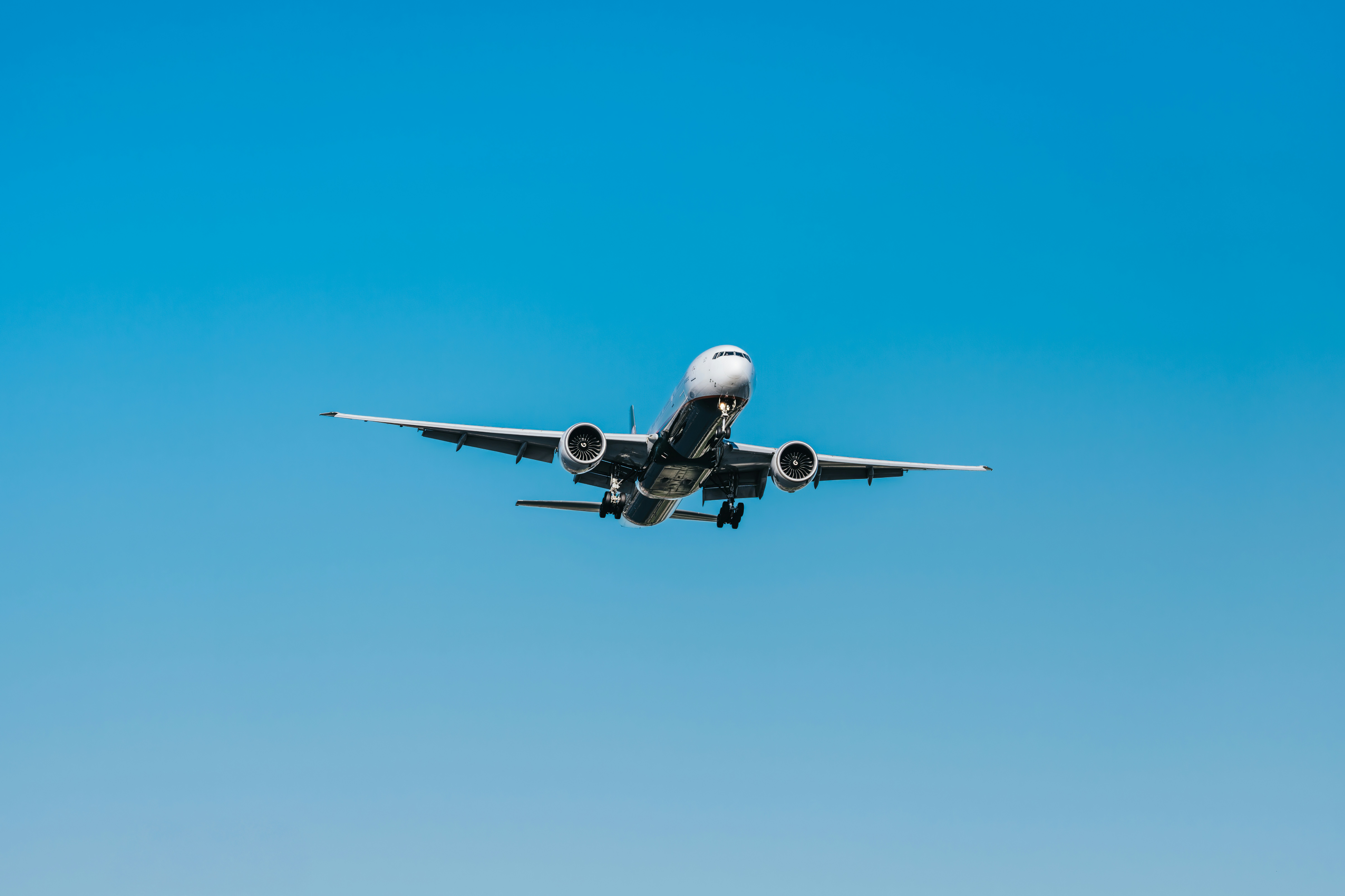 Commercial airplane flying under a bright blue sky