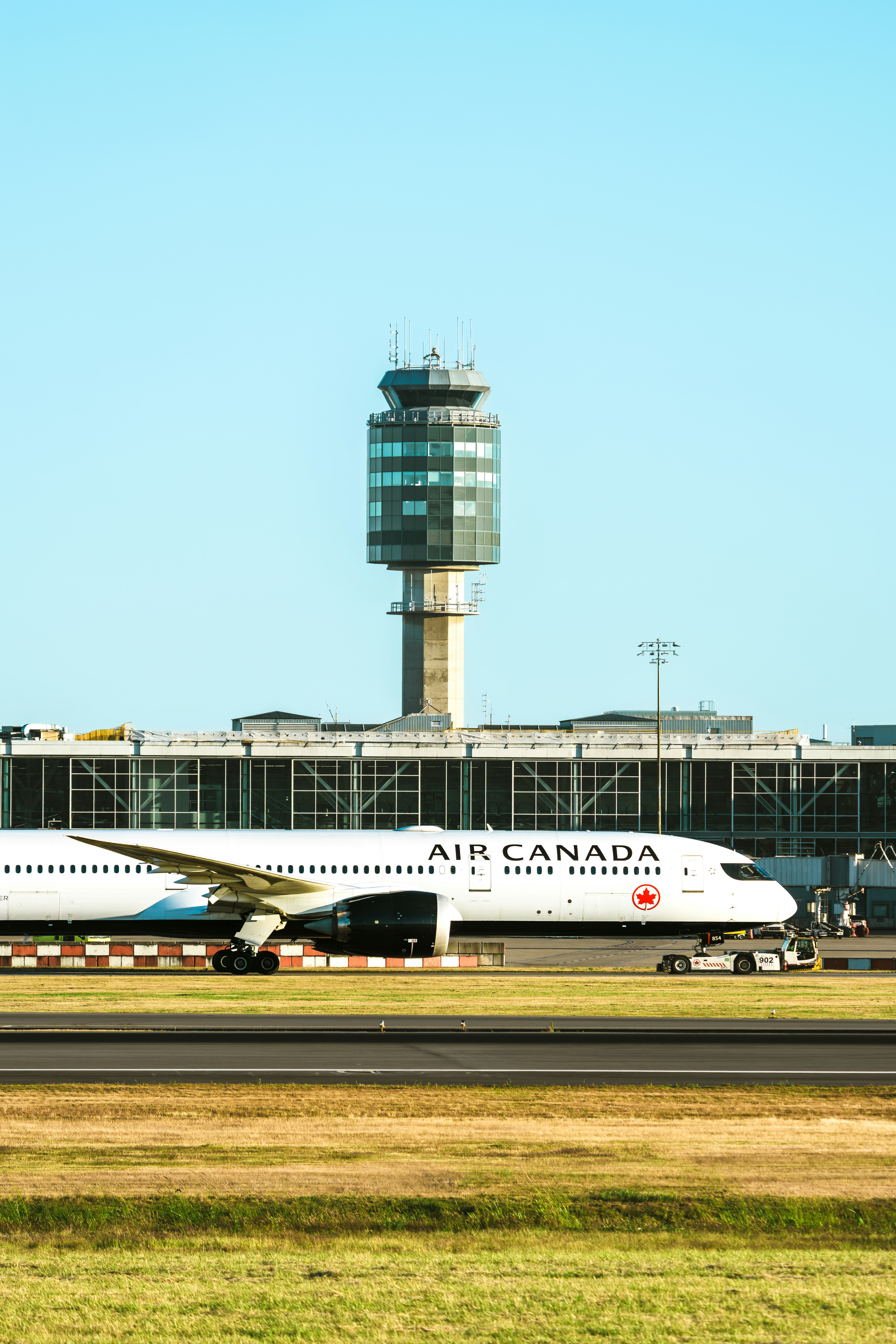 Air canada airplane on airport tarmac with control tower.