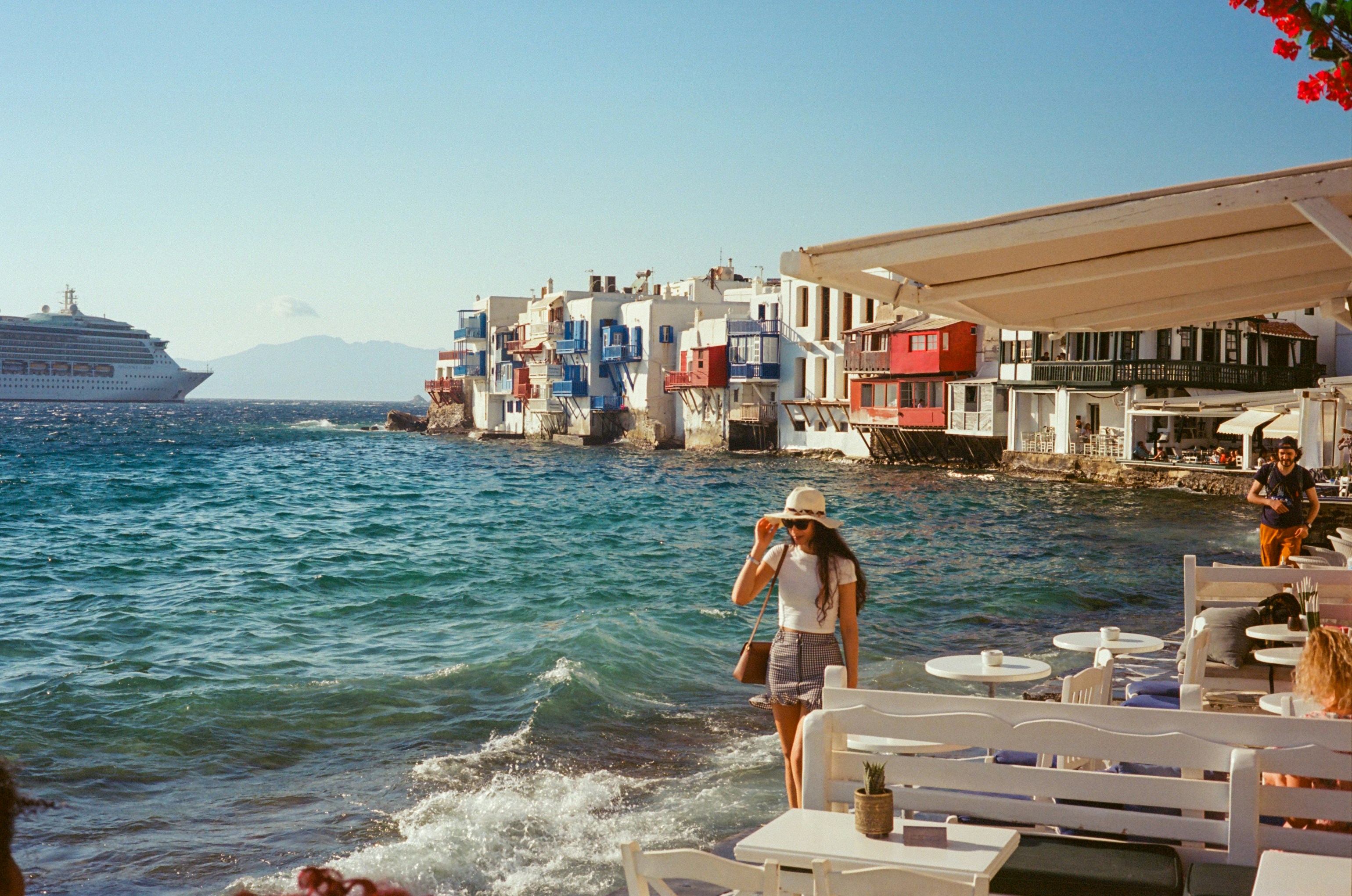 Woman by colorful coastal buildings and a cruise ship