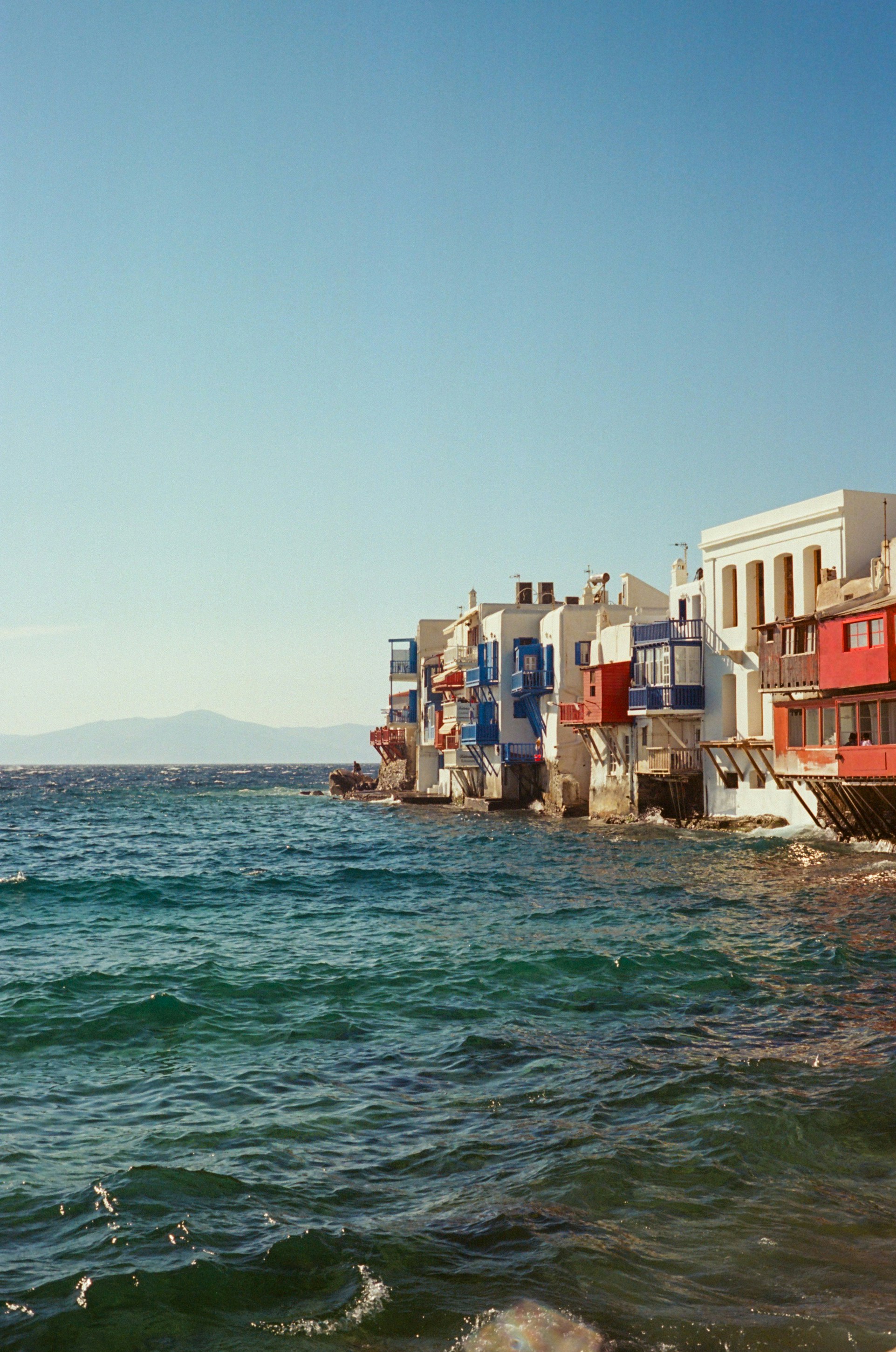 Edificios coloridos bordean el mar azul ondulado bajo un cielo despejado.