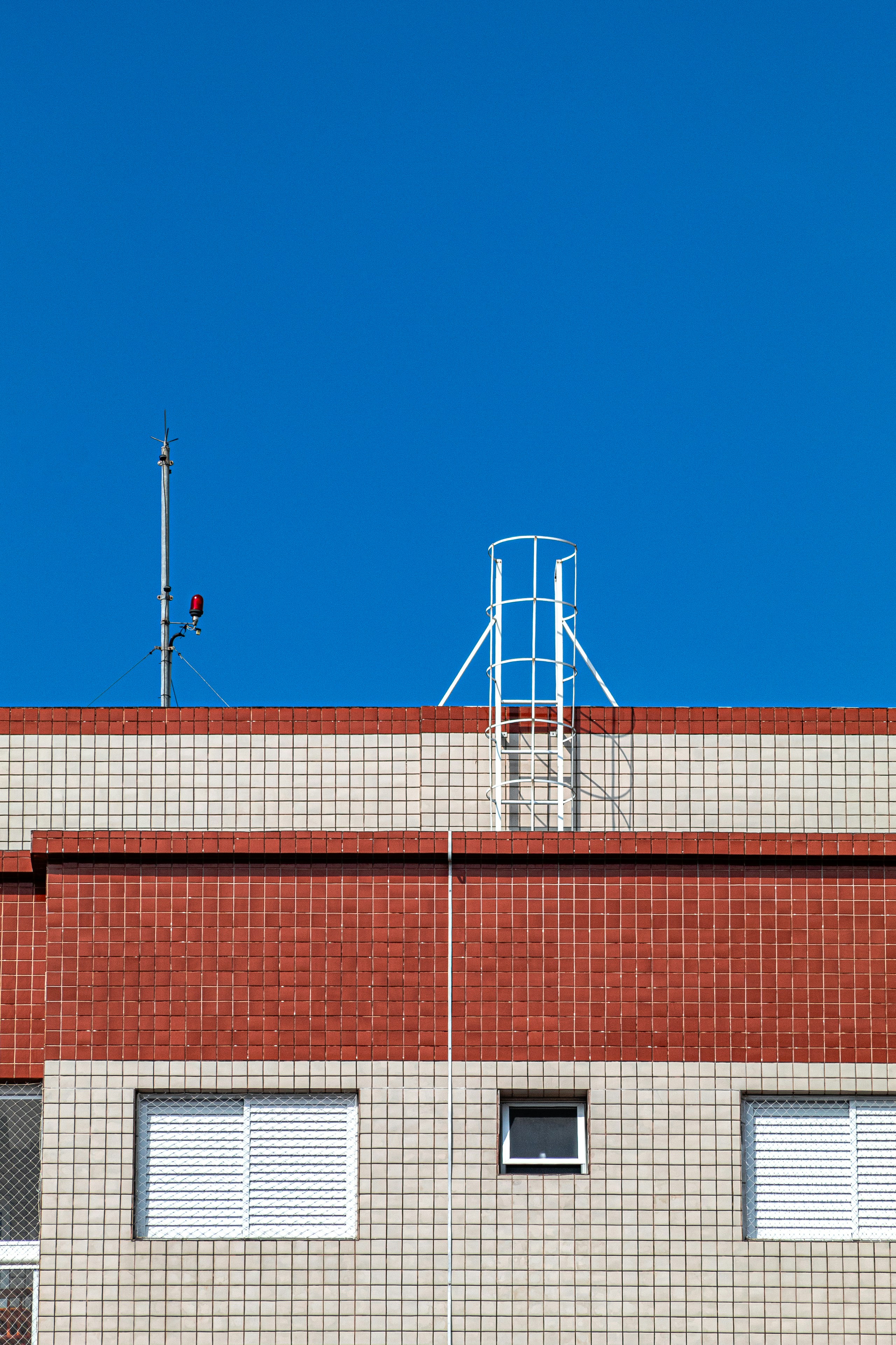 Red and beige tiled building under a clear blue sky.