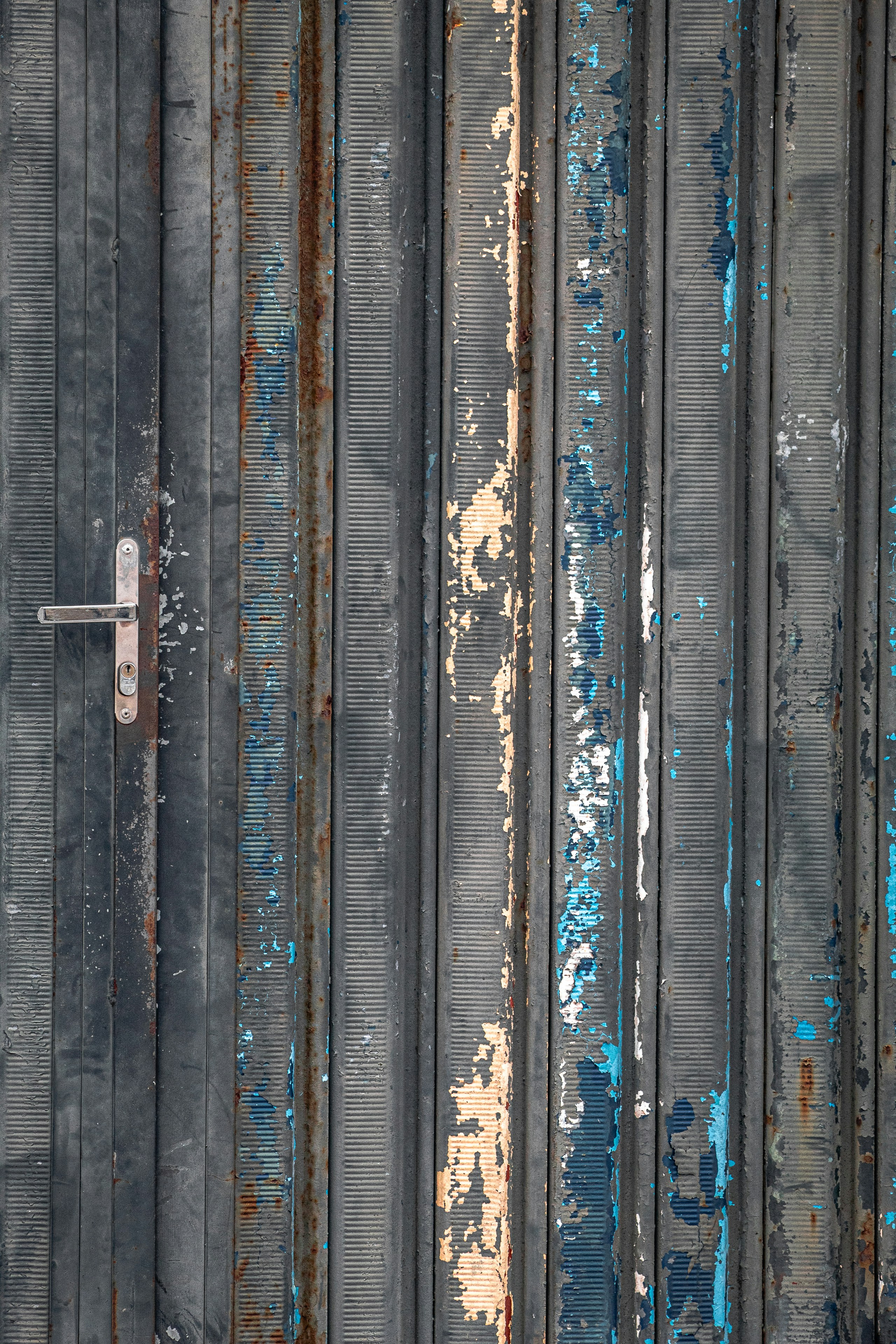 A rusty, peeling metal door with a silver handle.