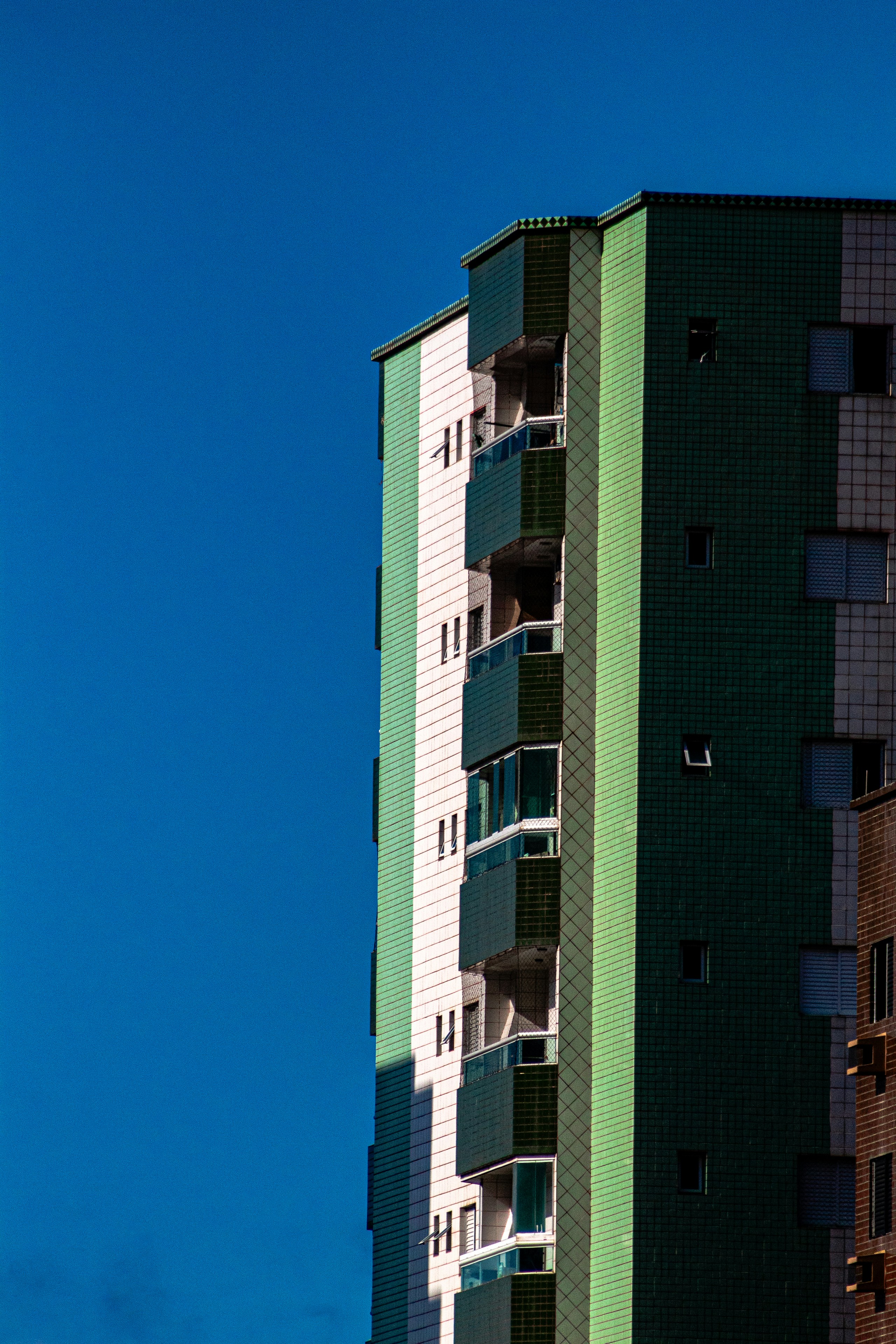 Modern building with green and white facade against blue sky.