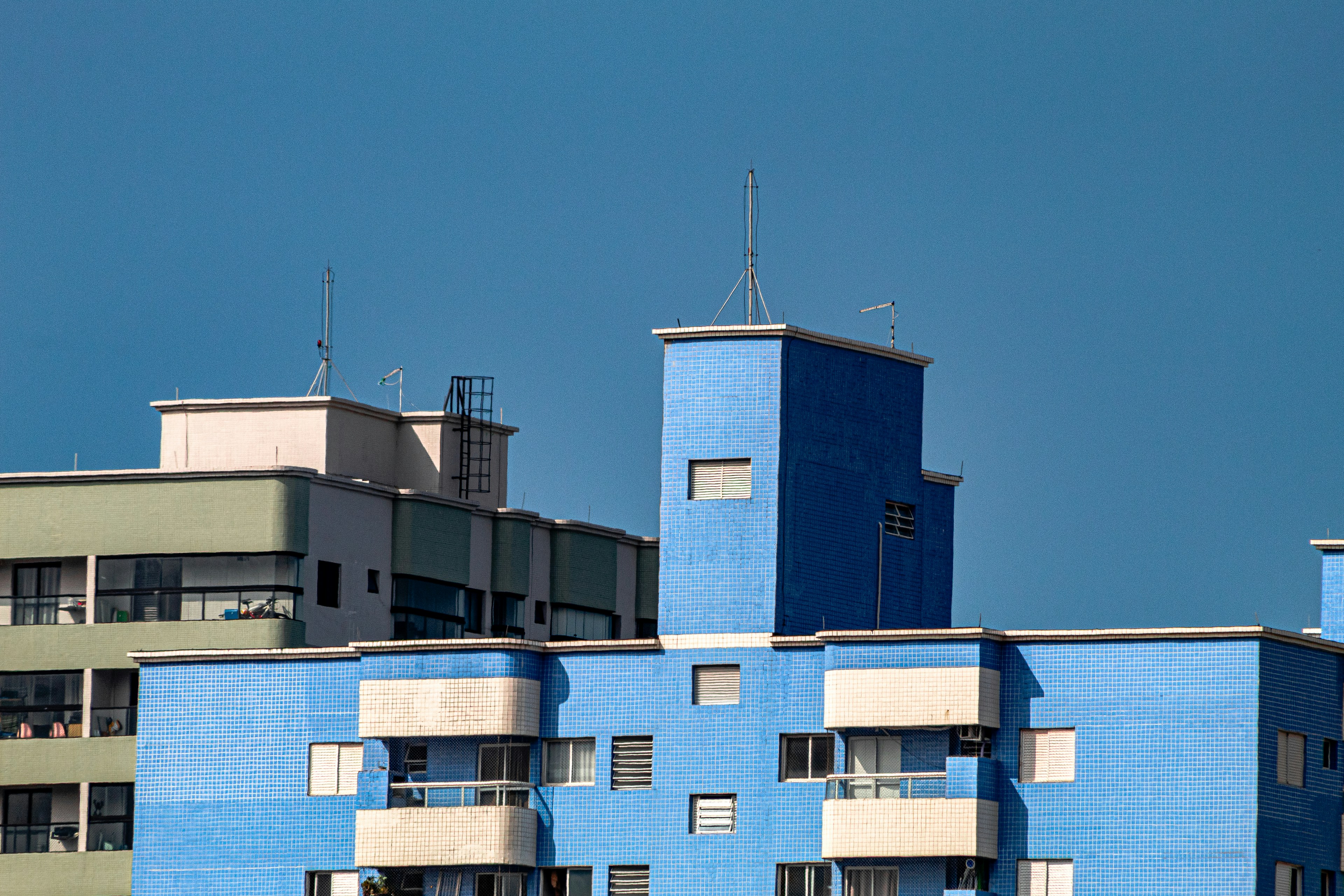 Blue and green buildings against a clear blue sky.