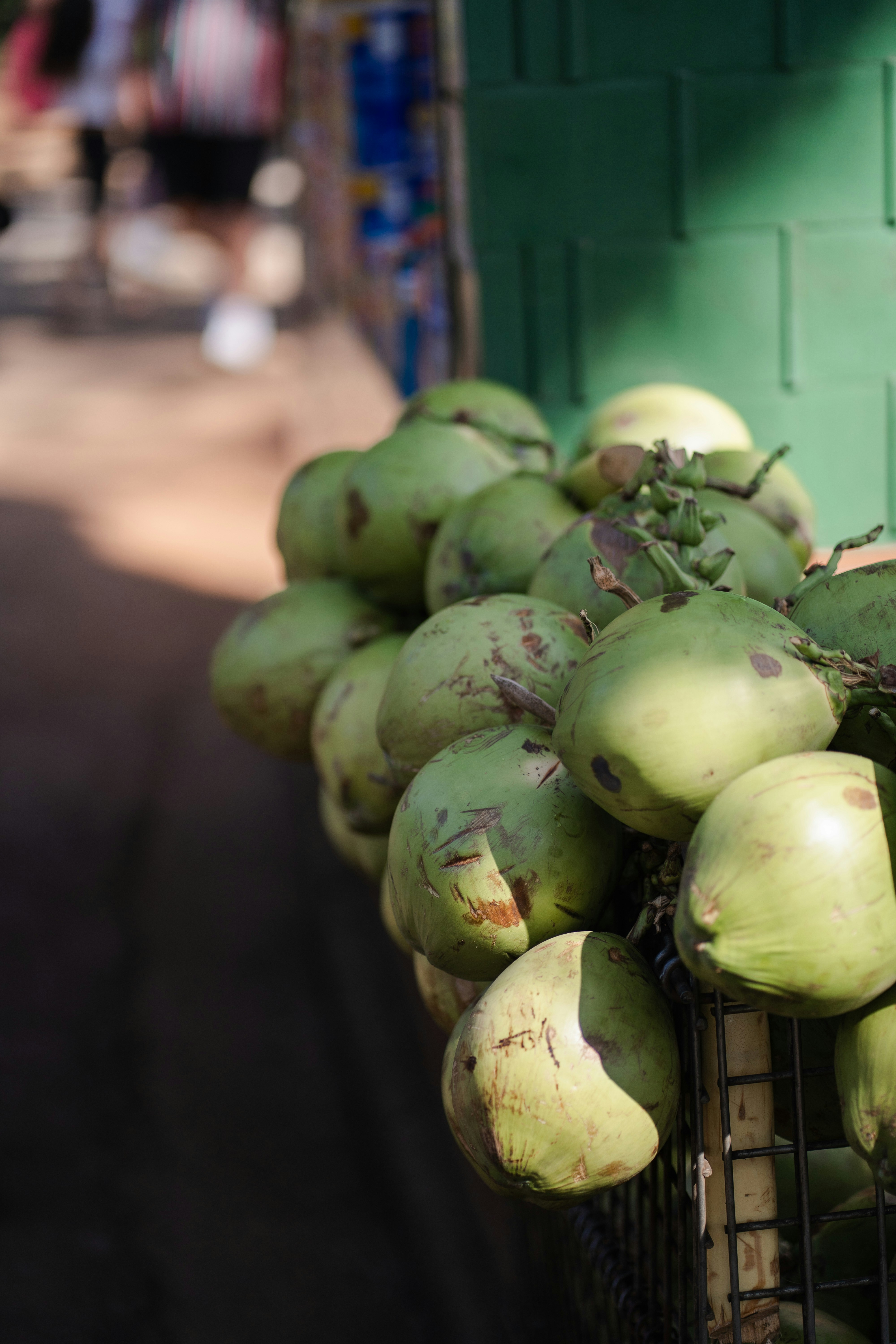 Noci di cocco verdi ammucchiate su una bancarella al sole.