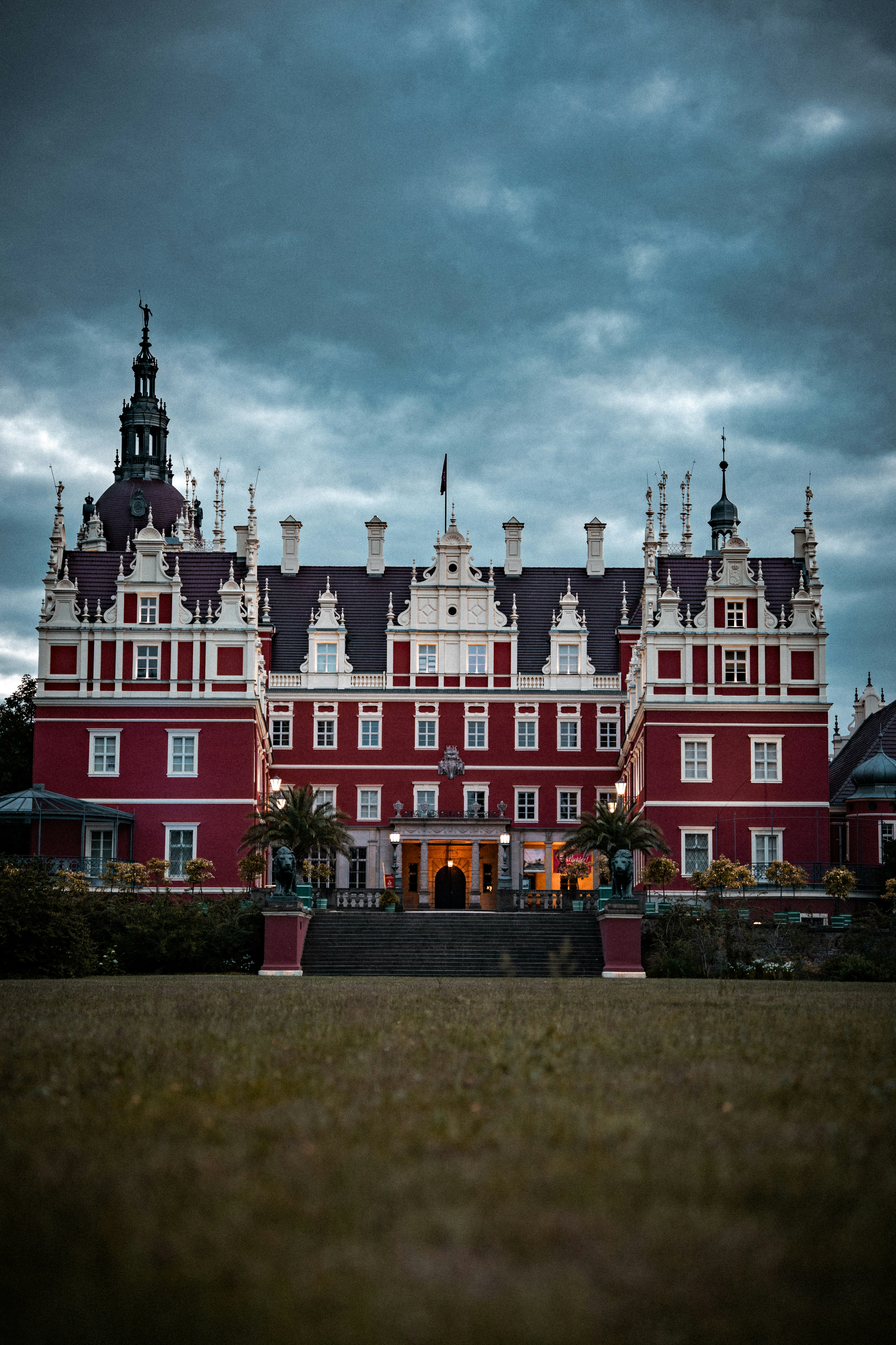 A grand red and white castle under a cloudy sky