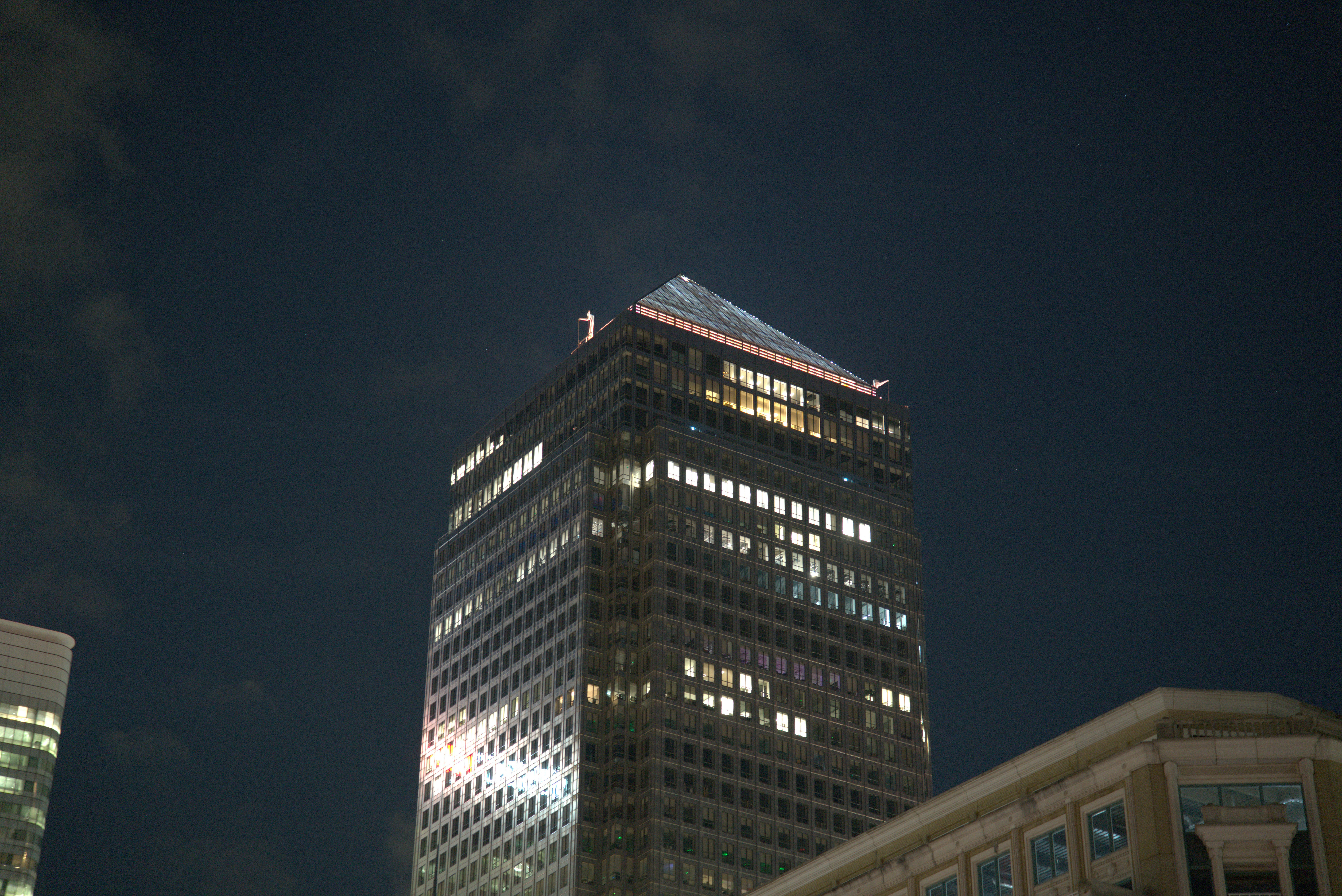 A tall office building with many lit windows at night.