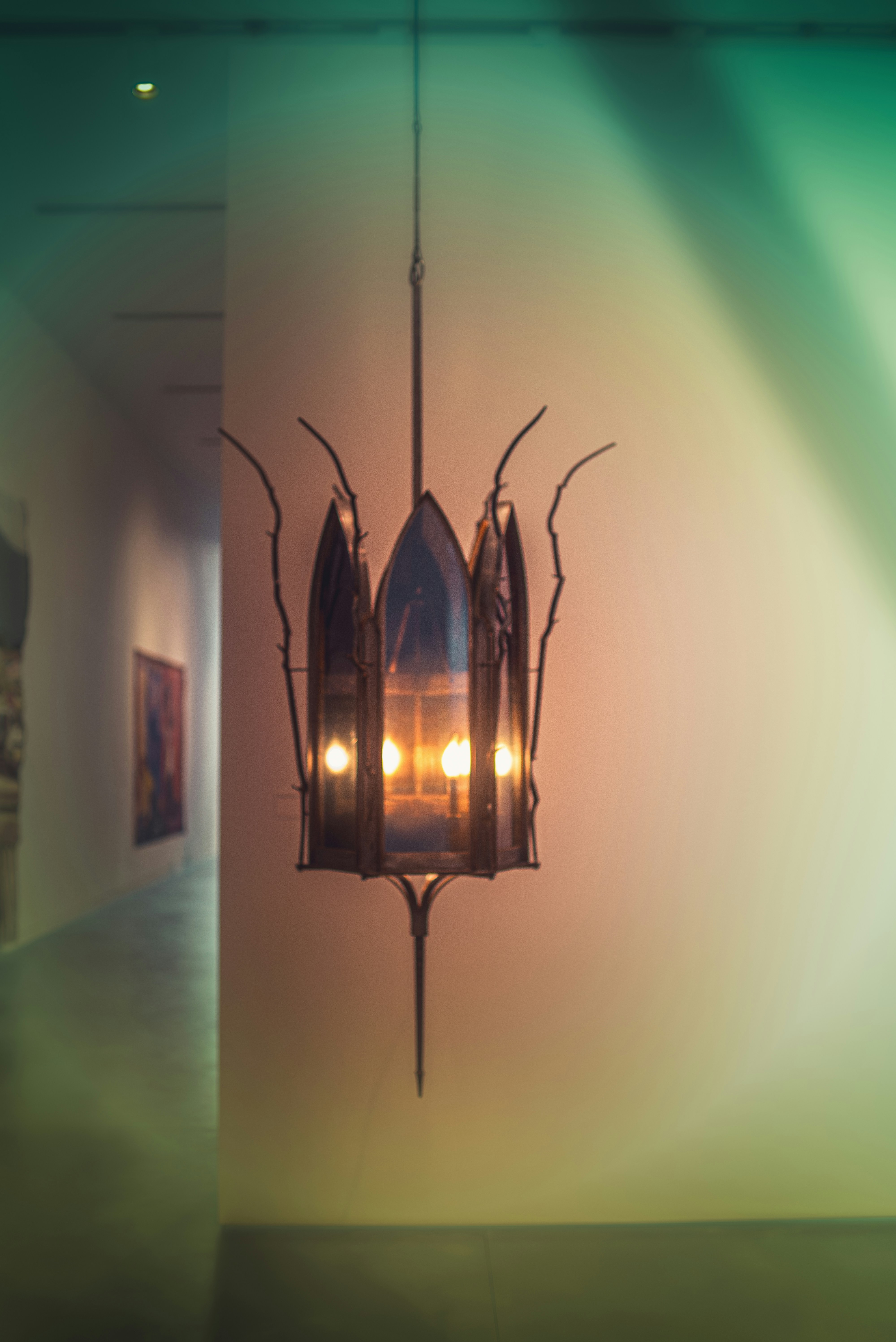 Ornate metal chandelier with warm glow in an art gallery.