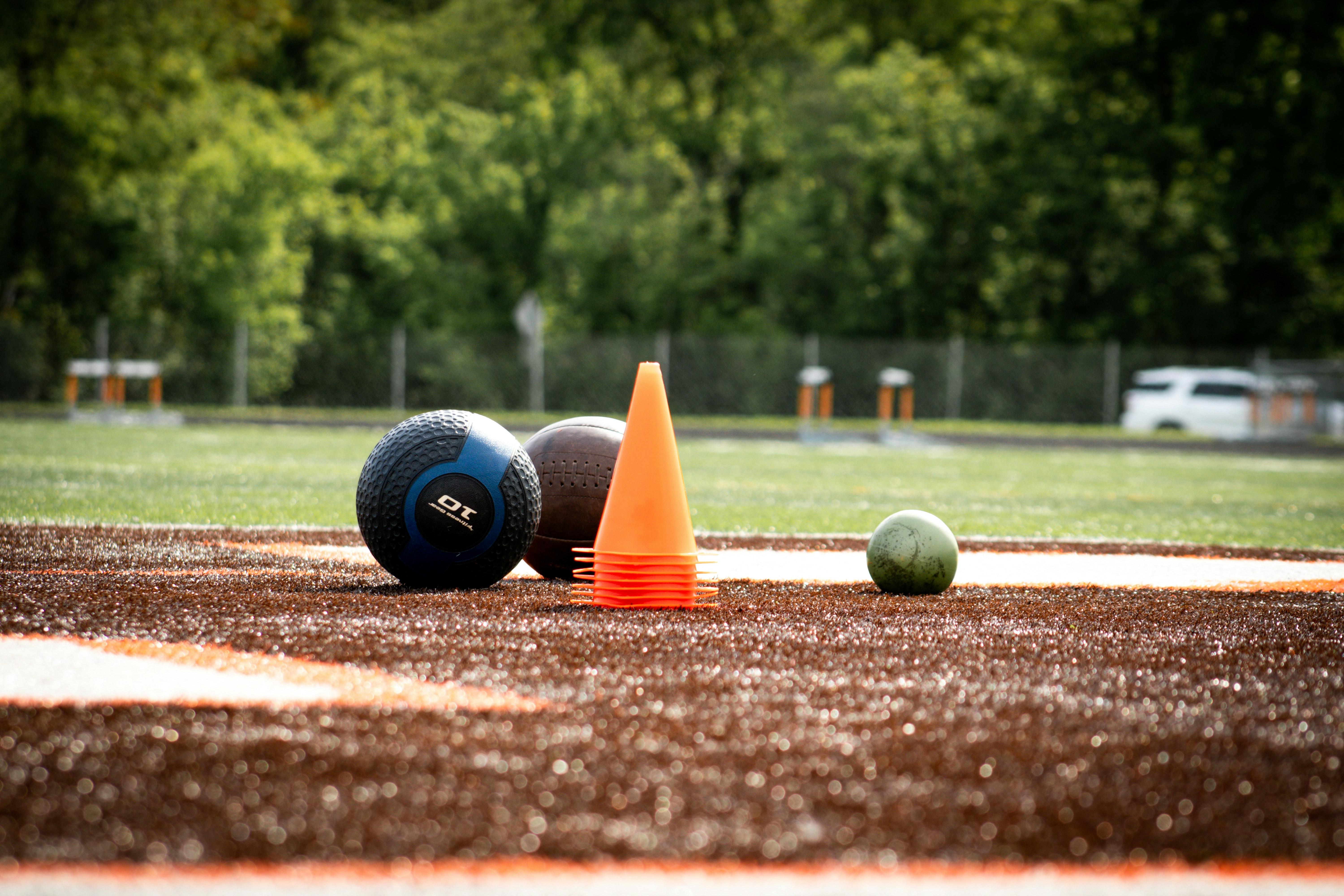 Medicine balls and an orange cone on a dirt track.