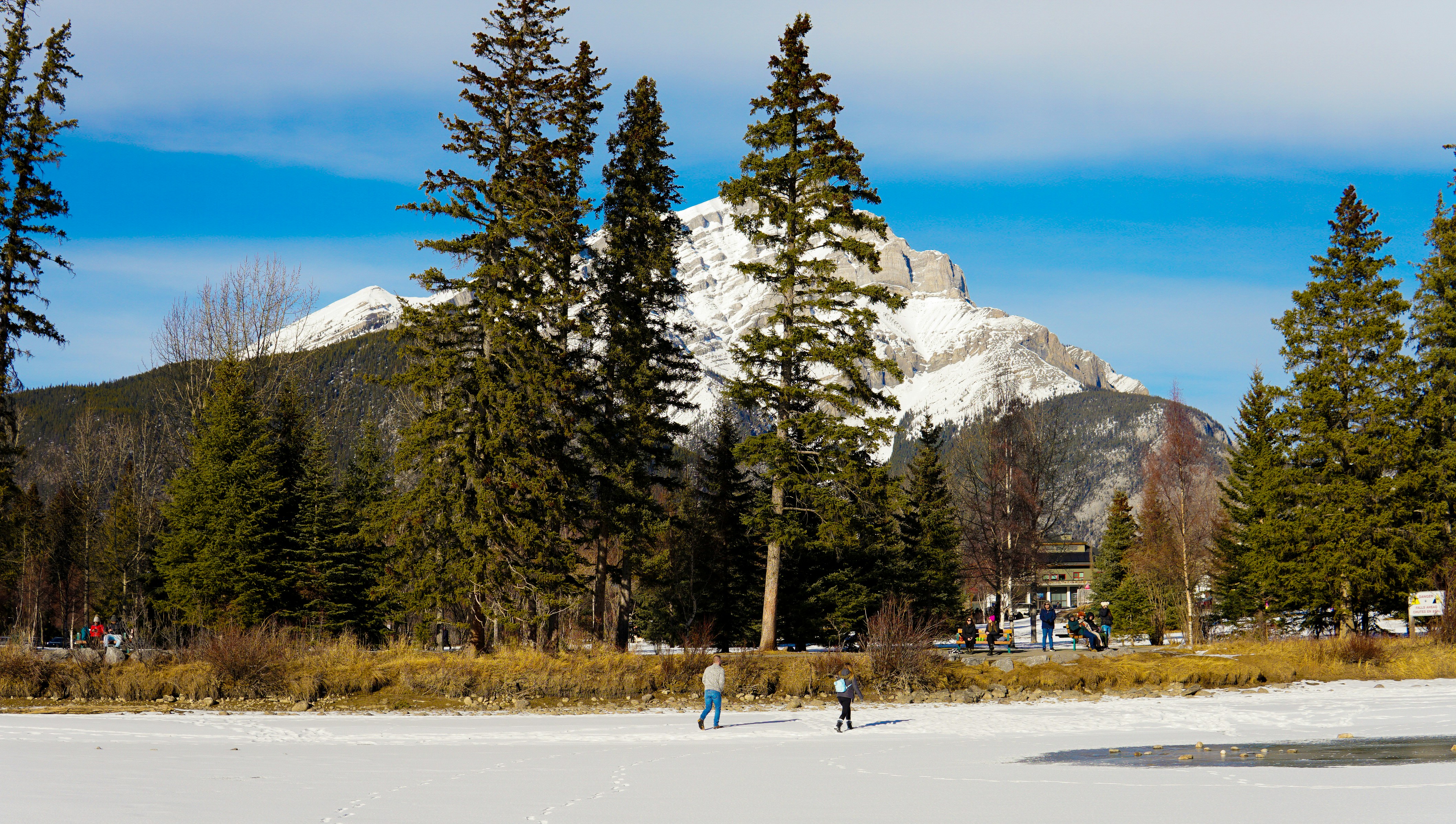 Ice skaters on a frozen lake near snow-capped mountains