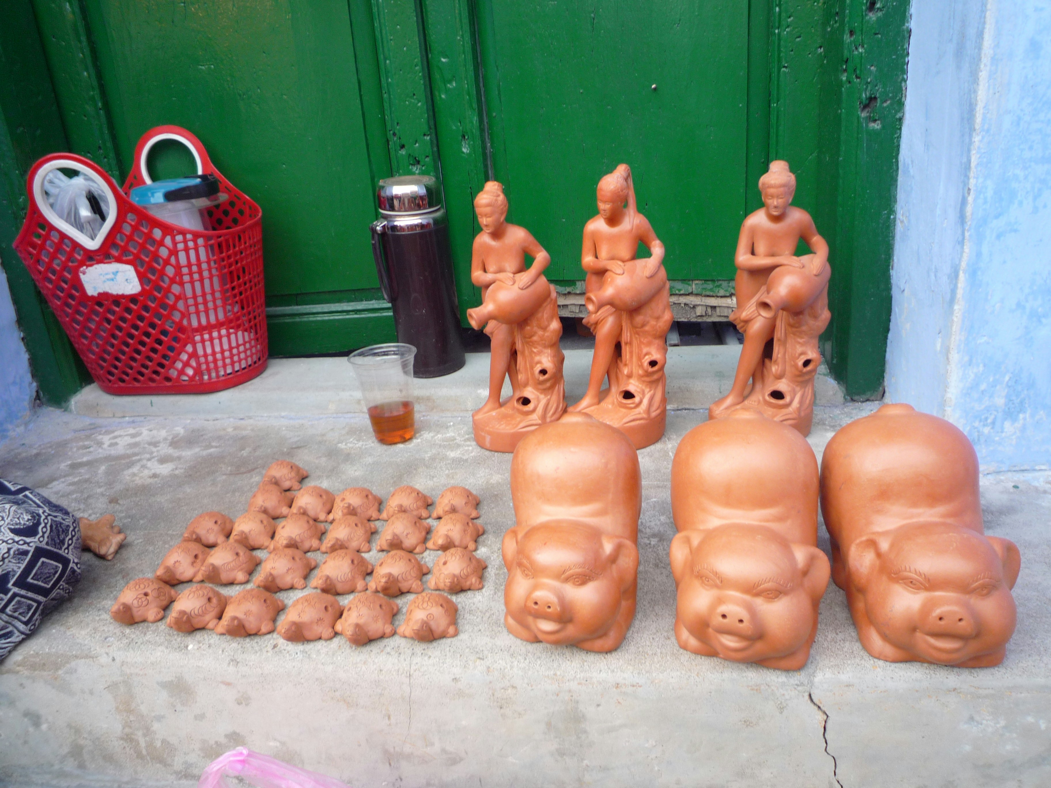 Des figurines en terre cuite représentant des personnes et des cochons exposées sur une marche.
