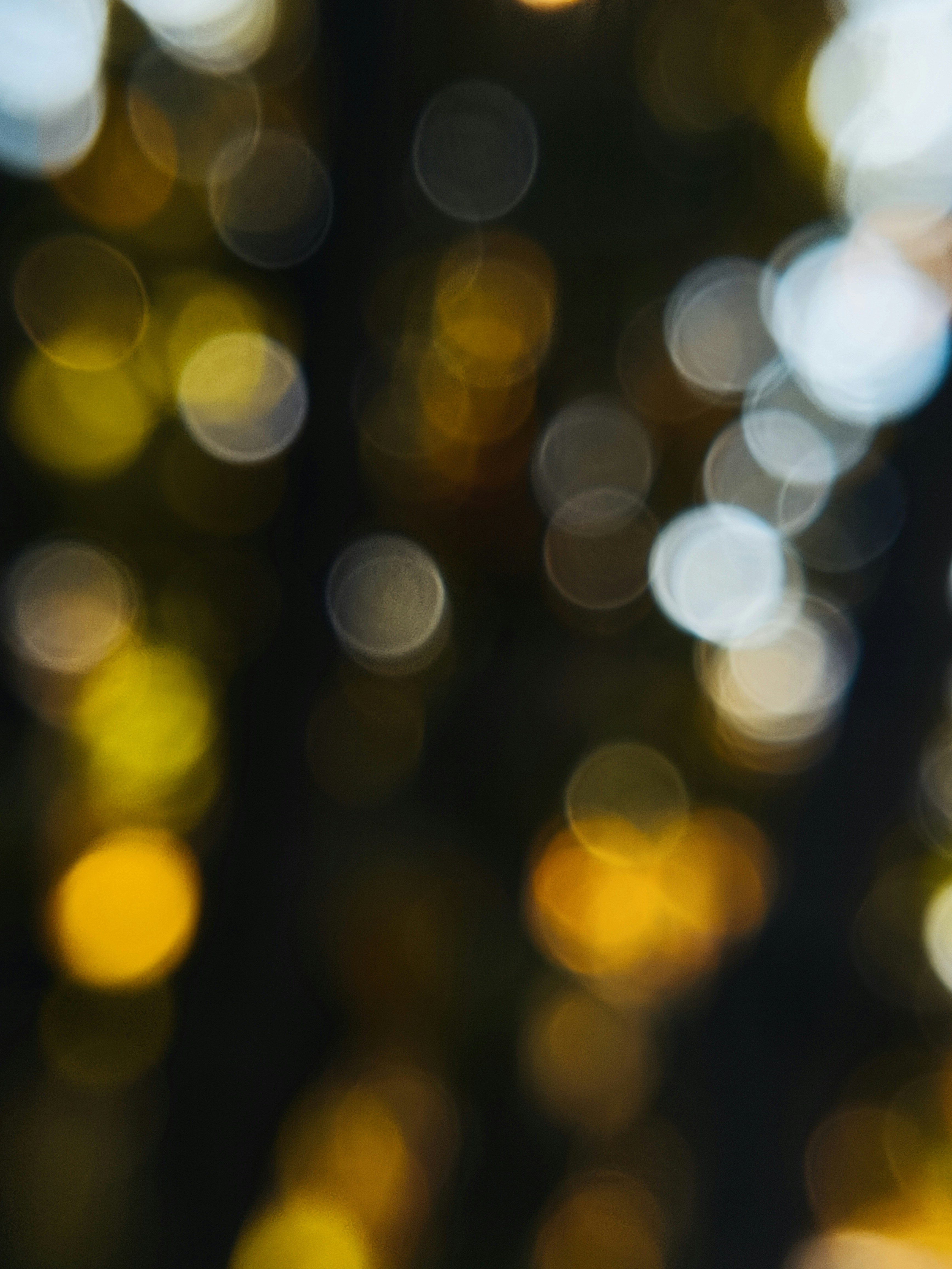Fond abstrait en bokeh avec des lumières dorées et blanches scintillantes.