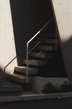 Concrete stairs with a metal railing and strong diagonal shadows