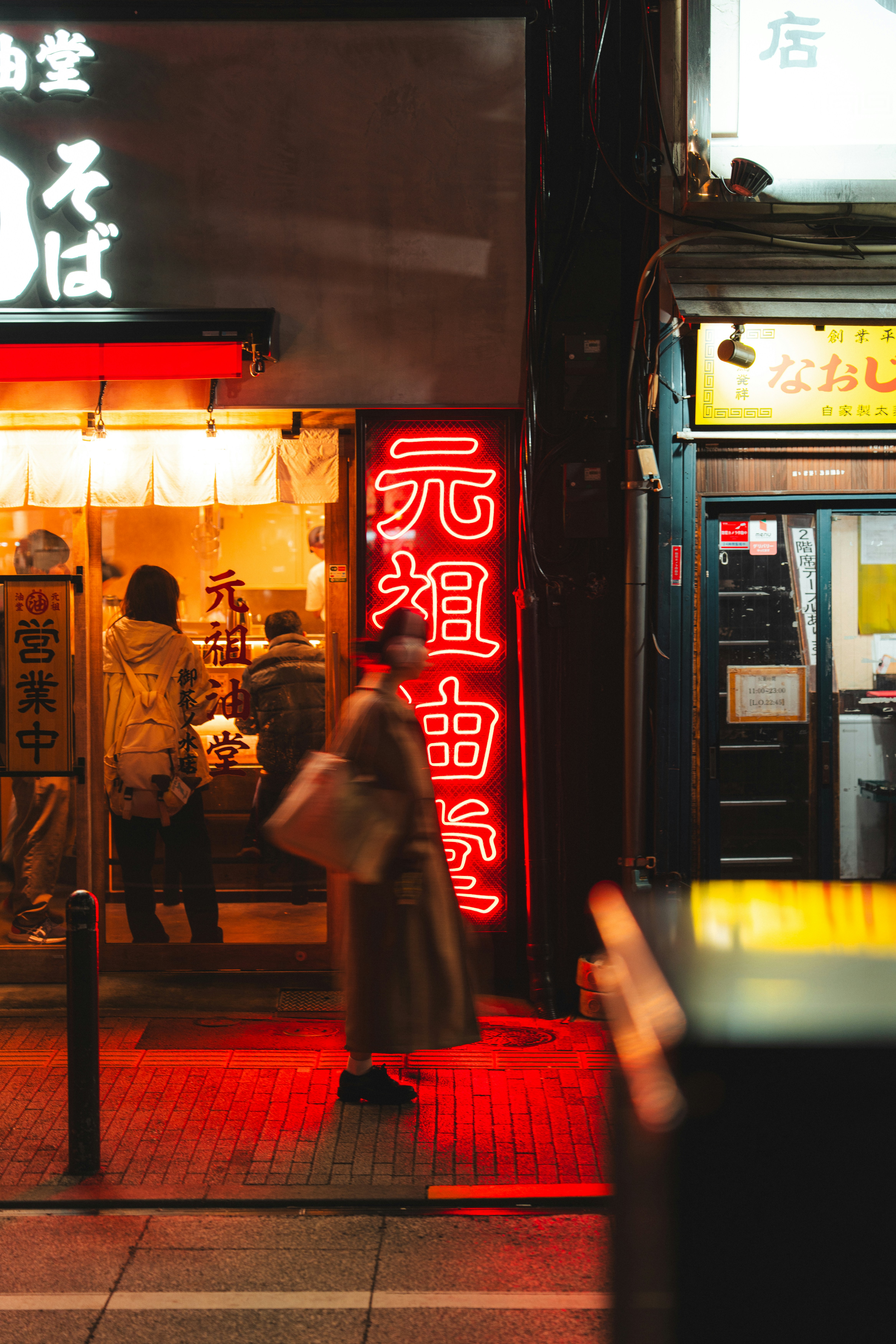 People walk past glowing neon signs and storefronts at night. - 相关推荐