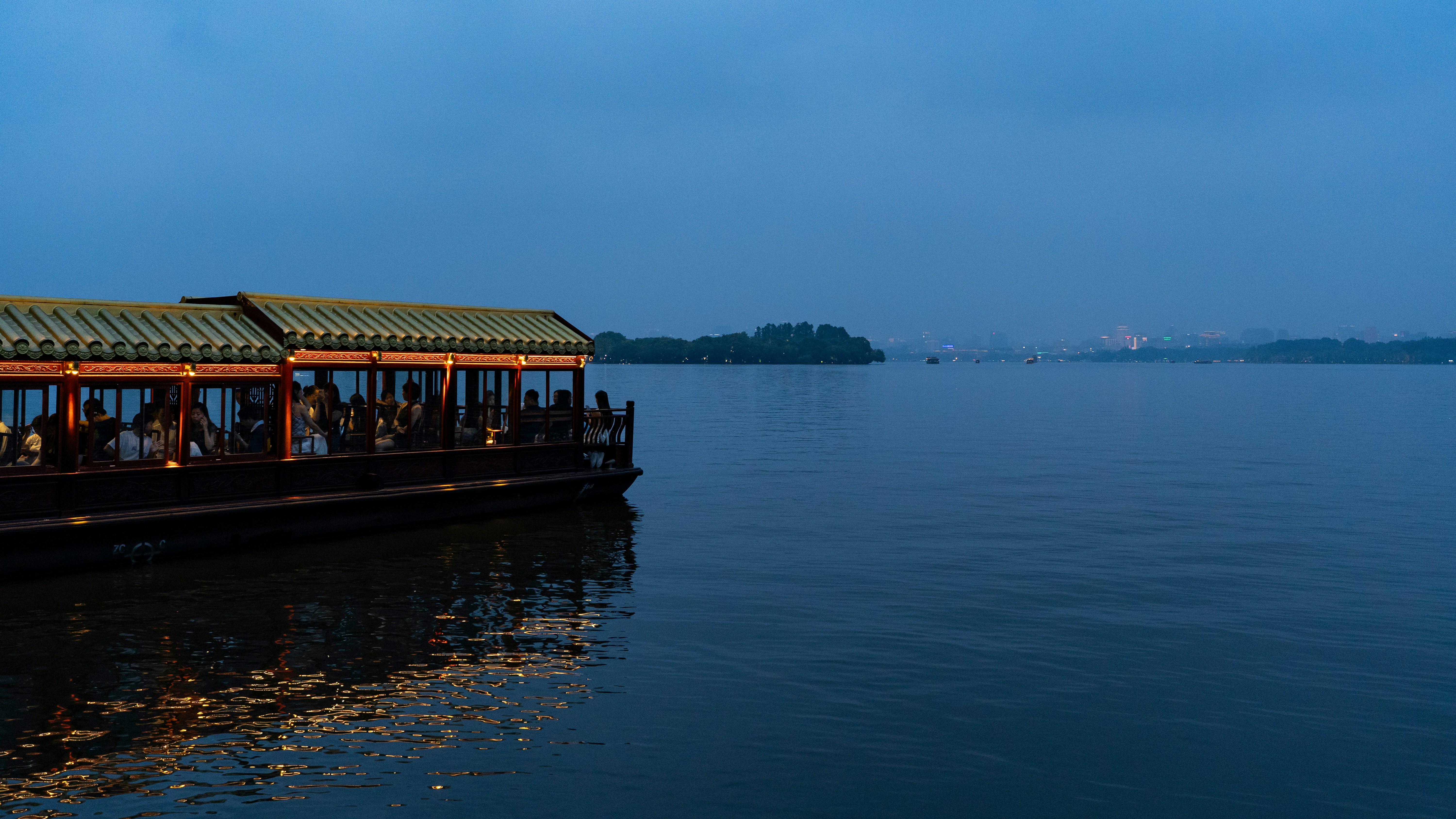 Illuminated traditional boat with passengers on calm lake