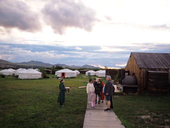 People on a wooden path in a yurt camp.