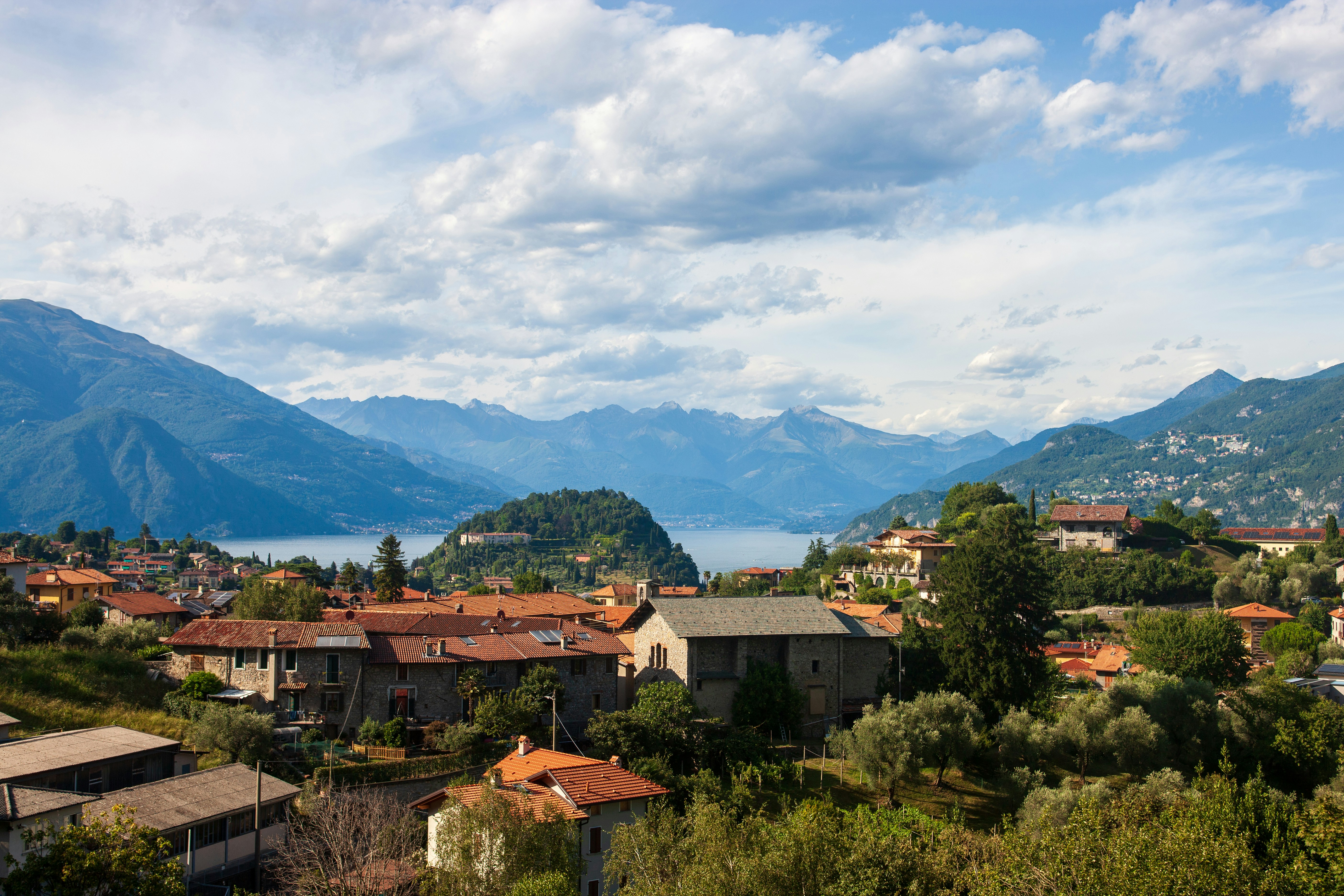 Village and lake surrounded by mountains under a cloudy sky.