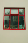 Red-framed window with plants and figurines on a light wall