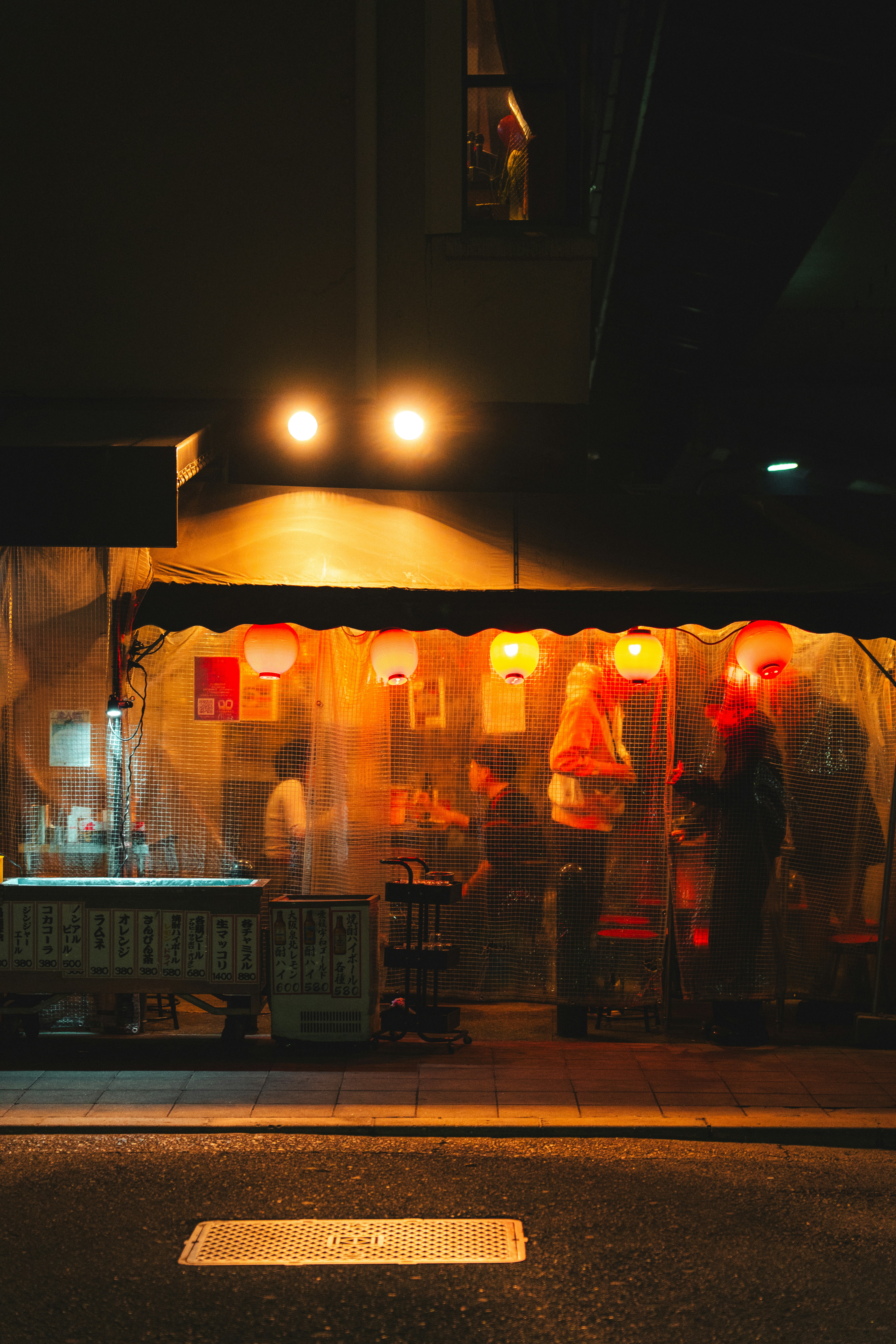 Warmly lit street food stall with red lanterns at night.