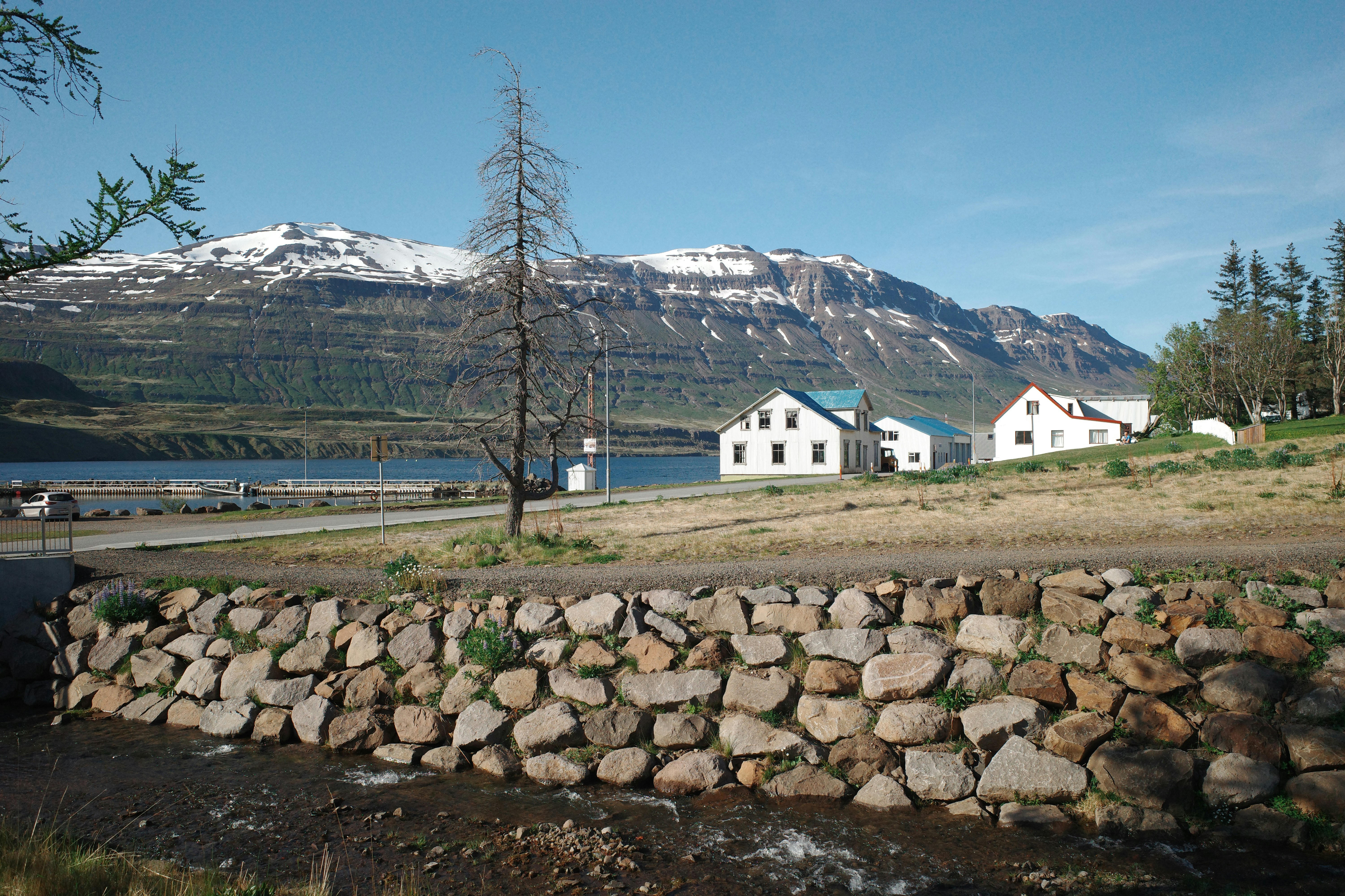 Village de fjord avec ses montagnes enneigées et un mur de pierre rustique.