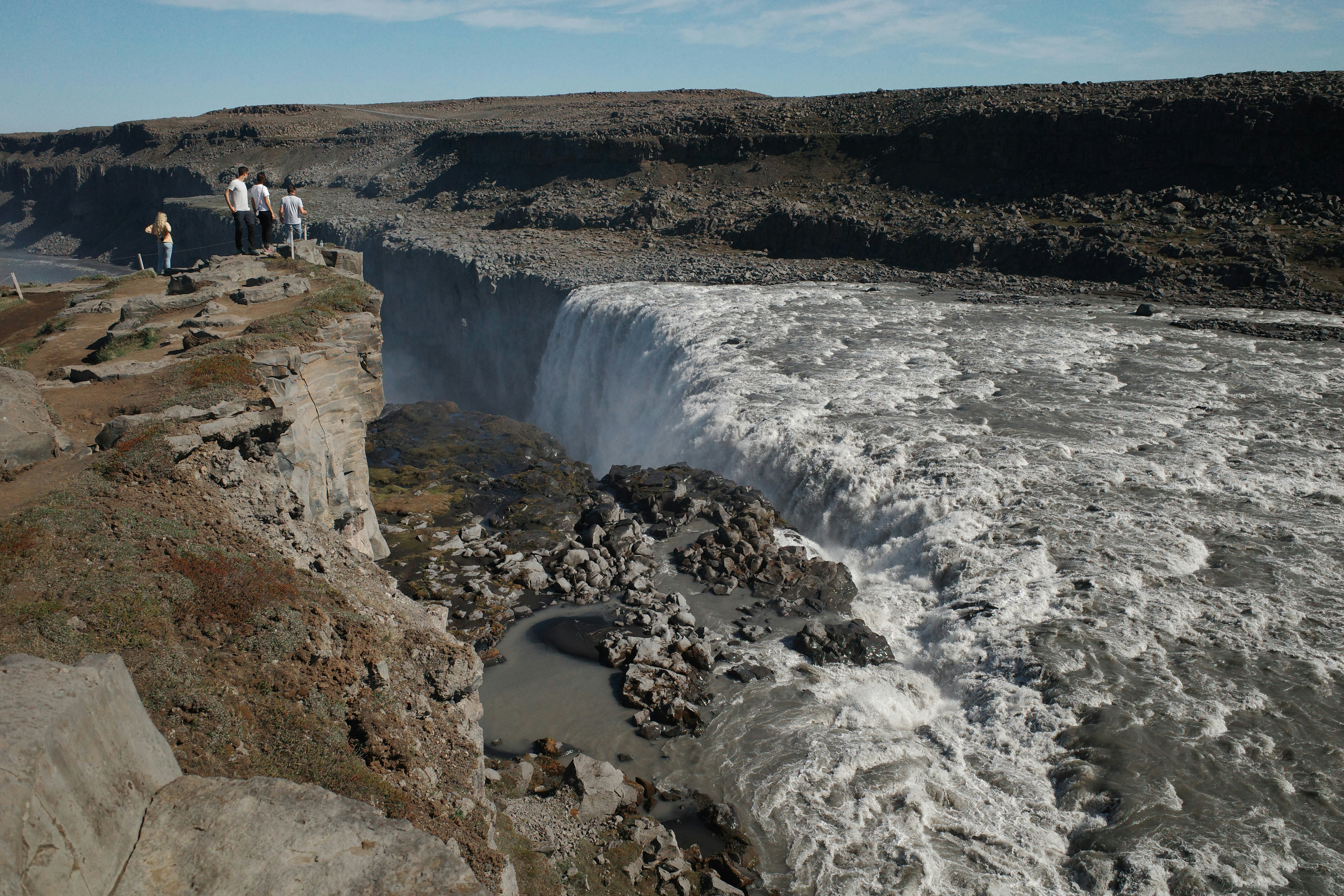 Les gens observent une puissante cascade depuis une falaise rocheuse.