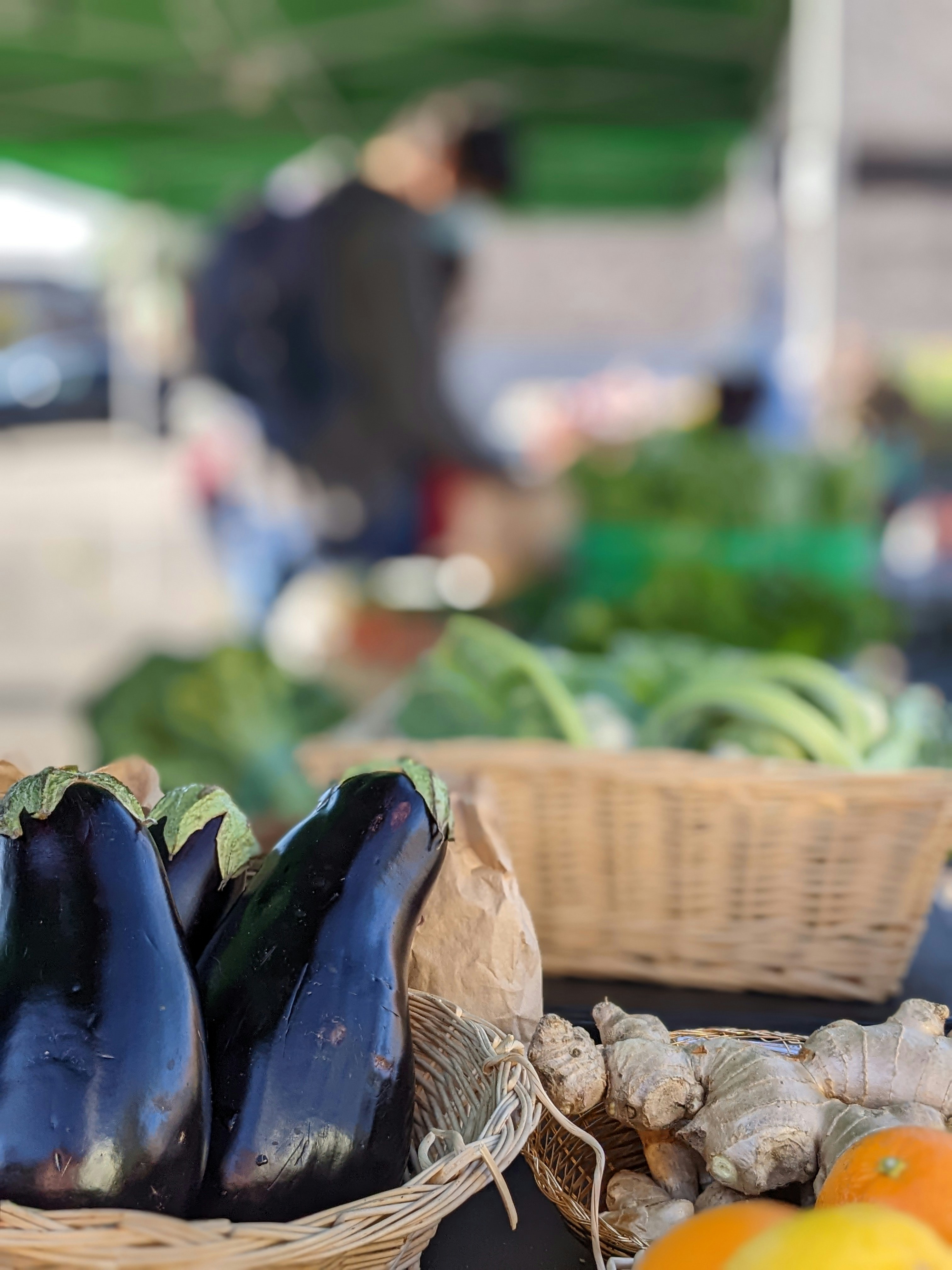 Fresh eggplants, ginger, and citrus at a vibrant market.