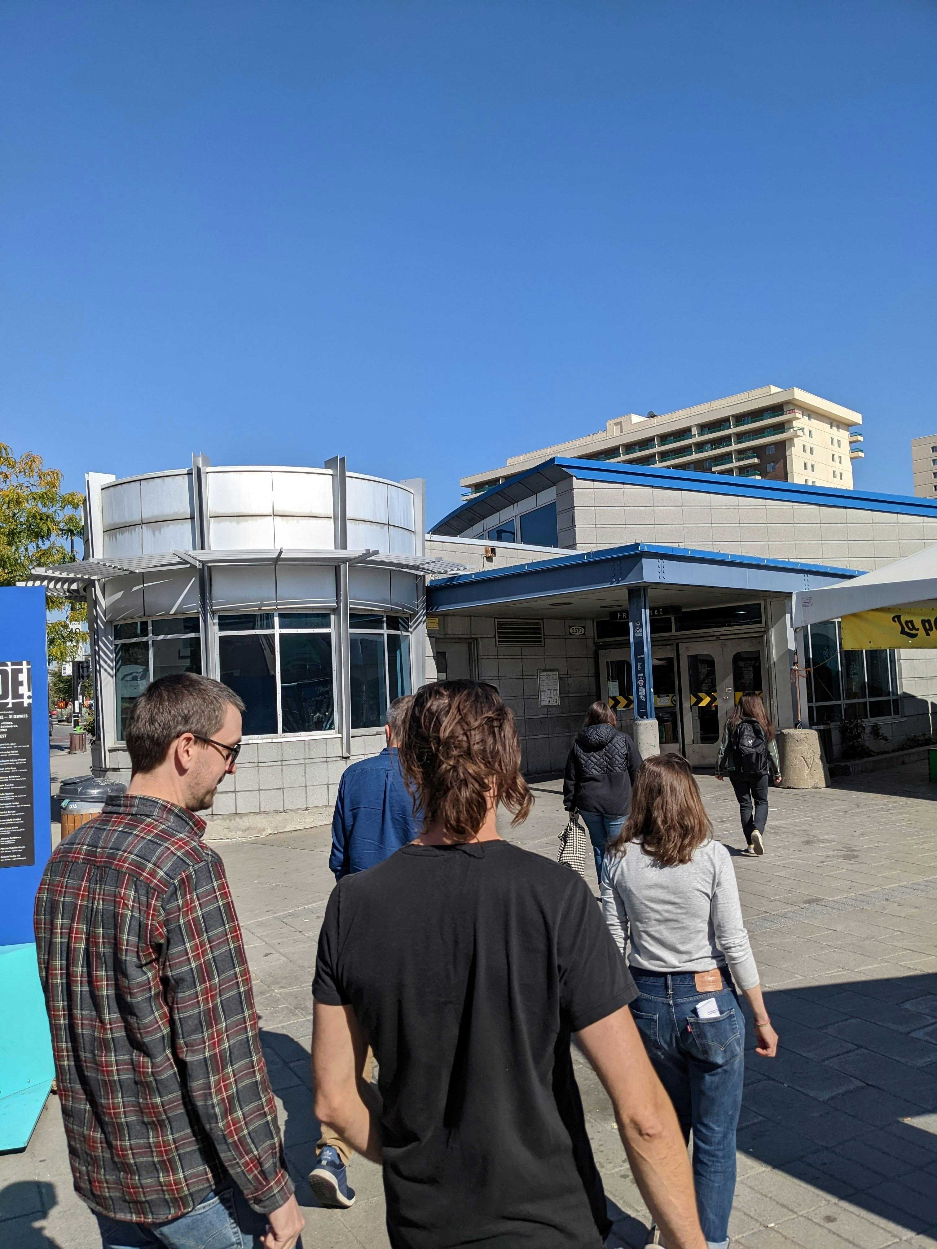 People walk towards a building entrance on a sunny day.