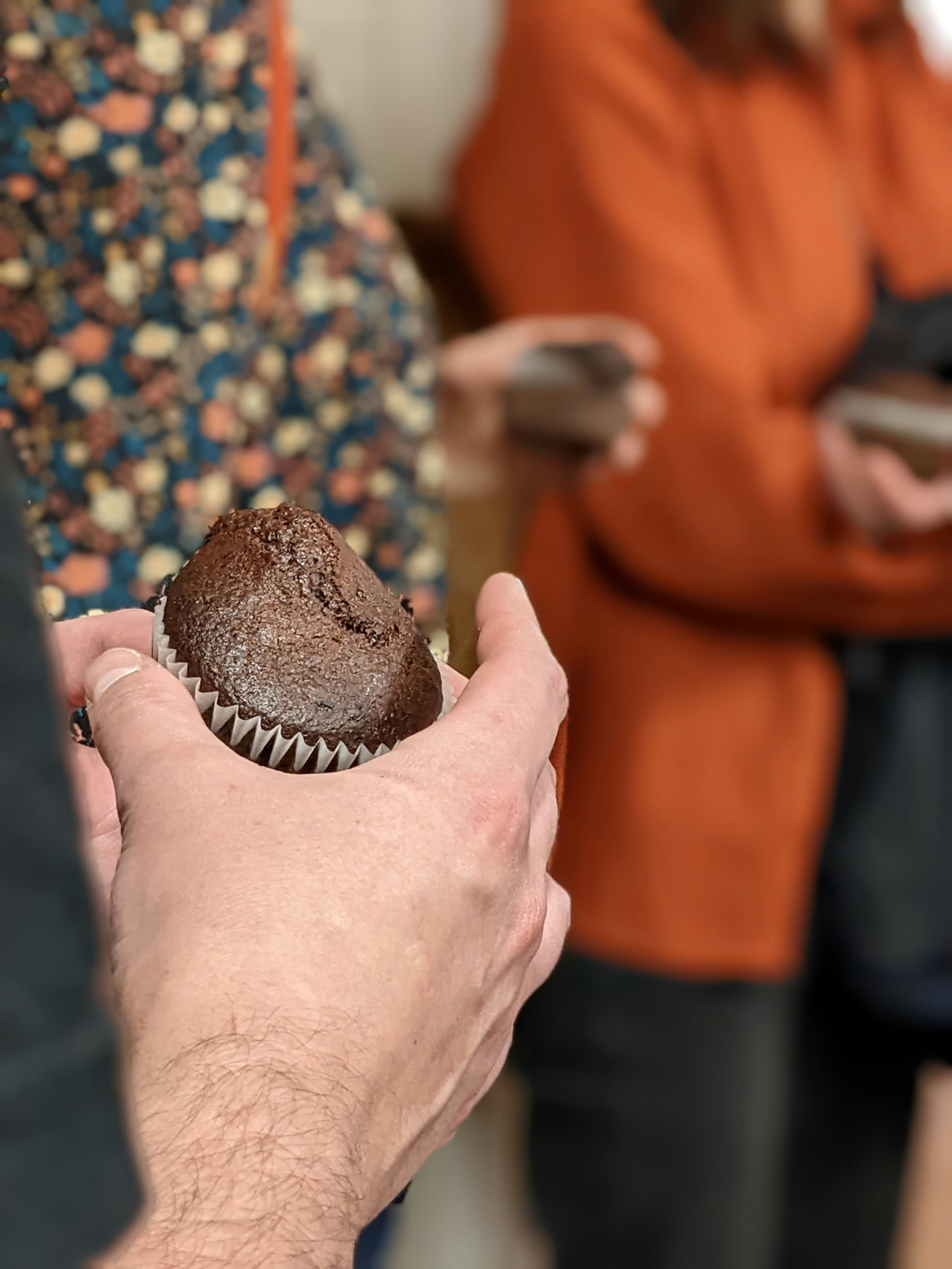 Hands holding a chocolate muffin.