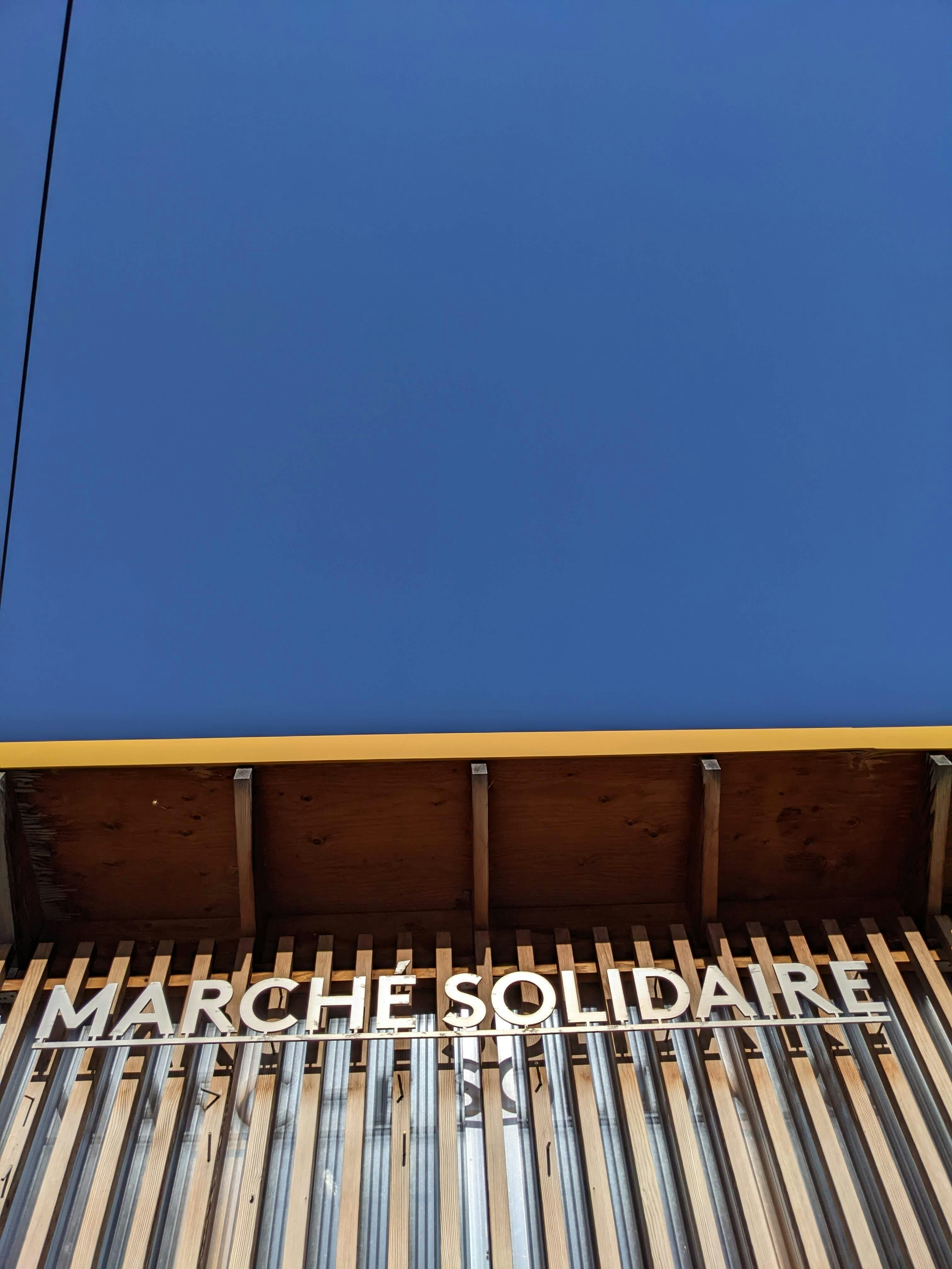 Blue sky above building with marche solidaire sign.