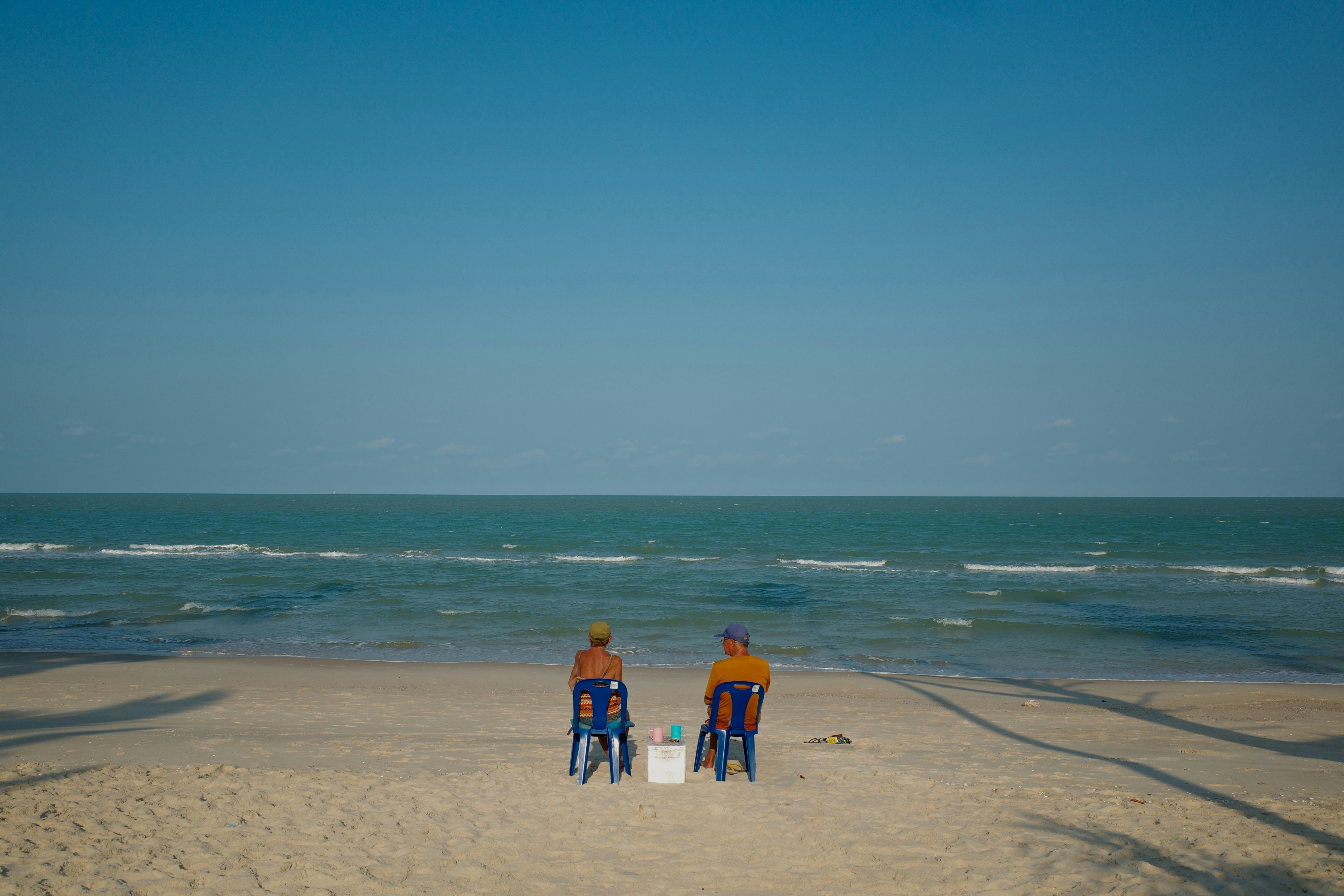 Duas pessoas sentadas em cadeiras de praia à beira do oceano