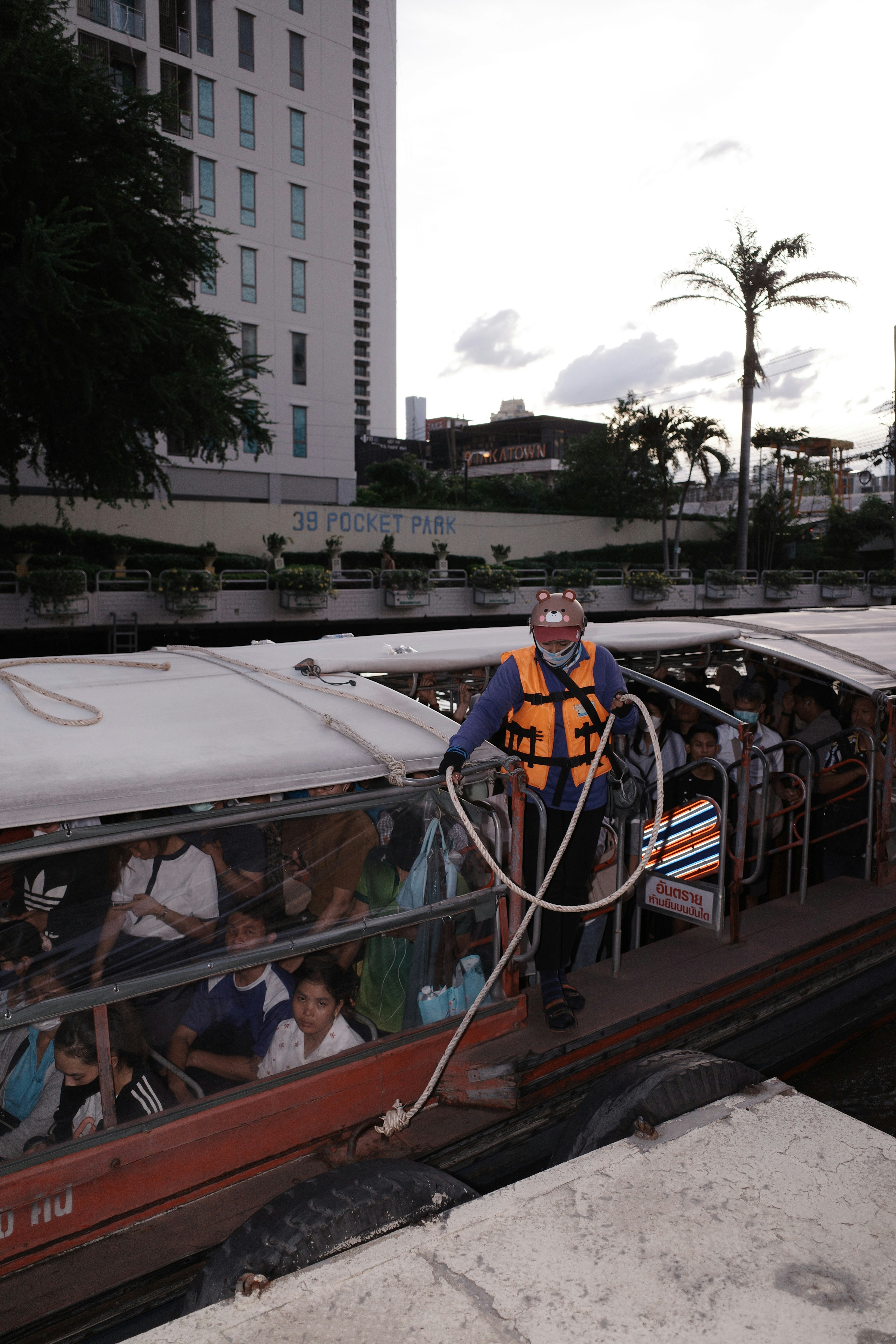 Pessoa de colete salva-vidas segurando barco de passageiros lotado