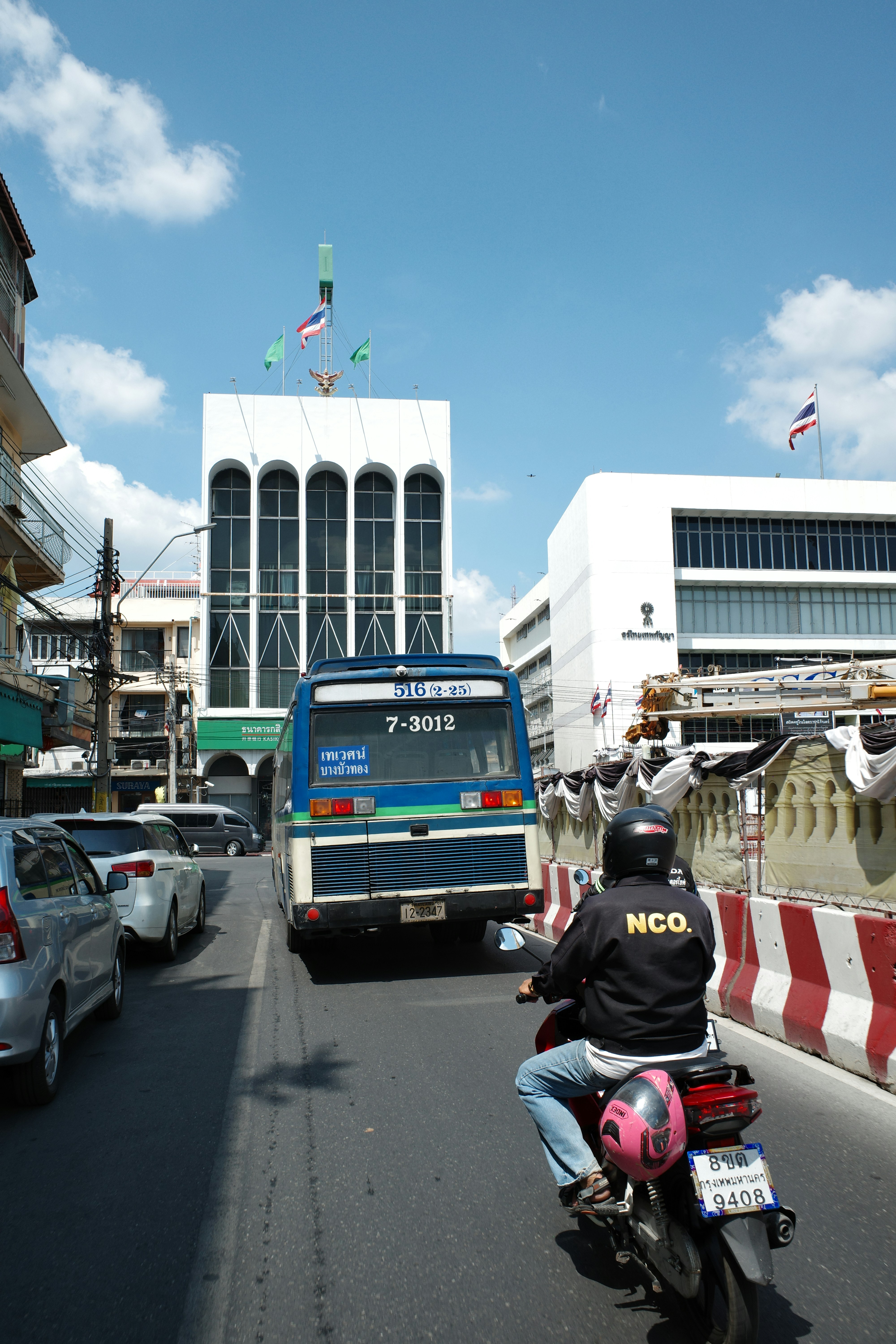 Moto e ônibus em uma rua movimentada da cidade