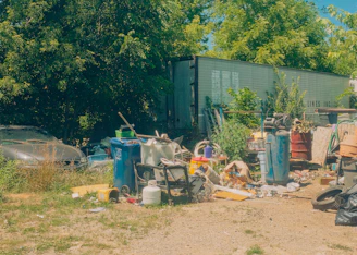 A cluttered yard with trash and a trailer house