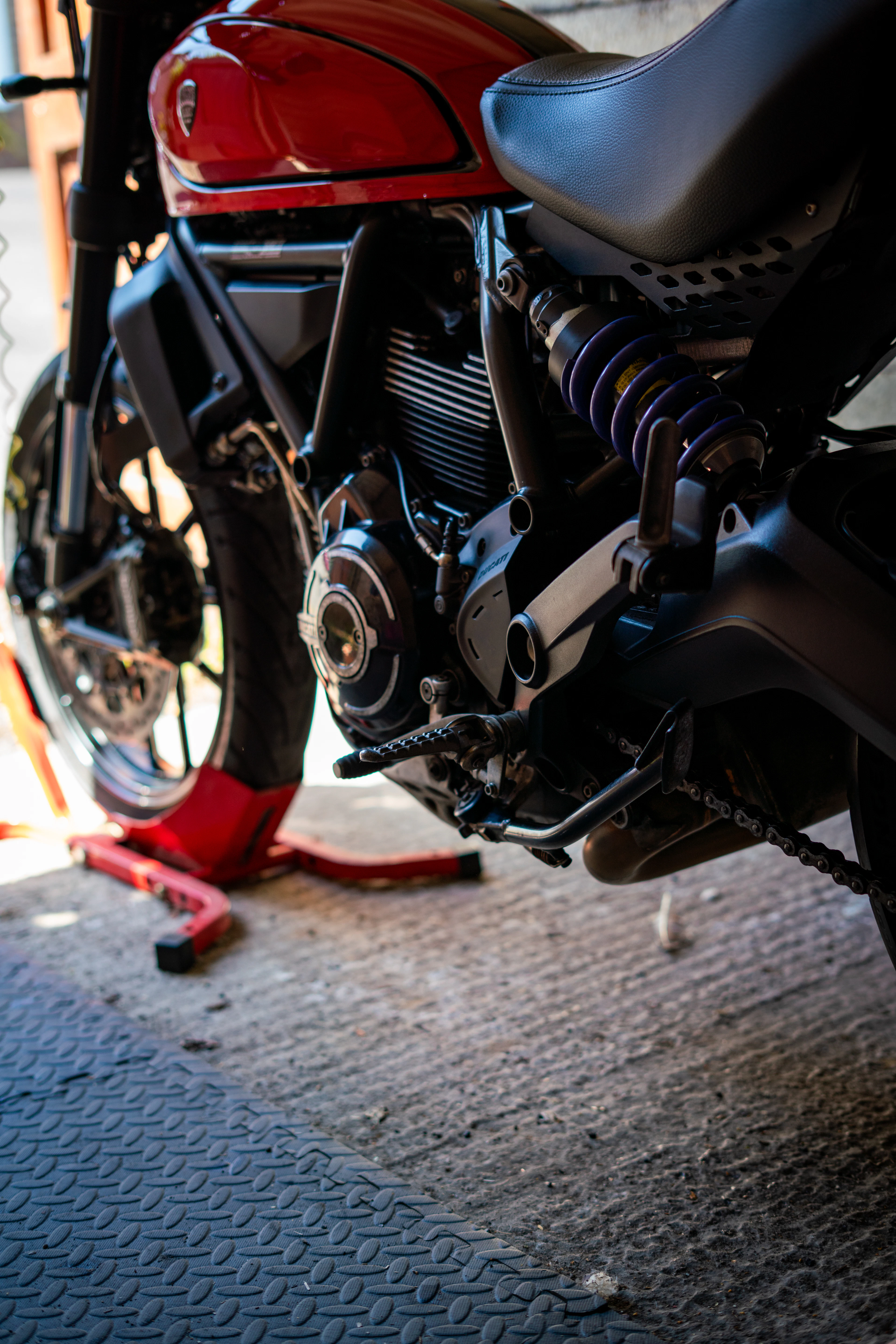 A motorcycle raised on a red rear paddock stand in a workshop