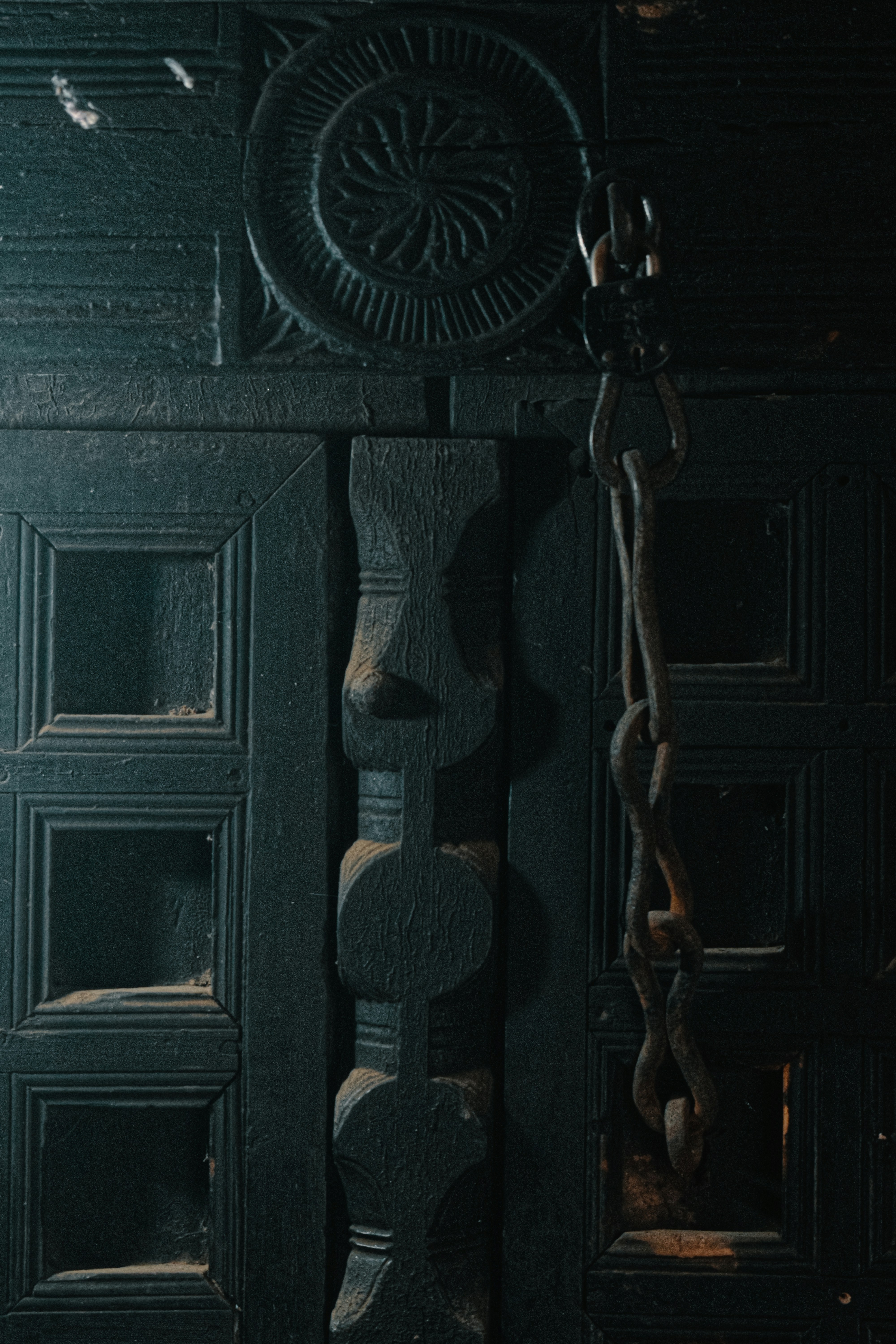 Ornate dark wooden door with carvings and a heavy chain.