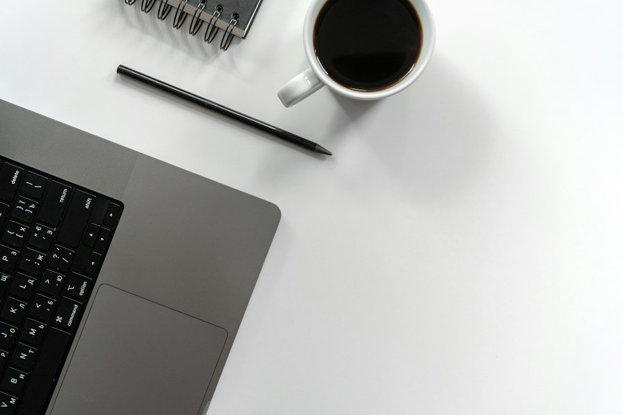 Laptop, notebook, pen and coffee on a white desk