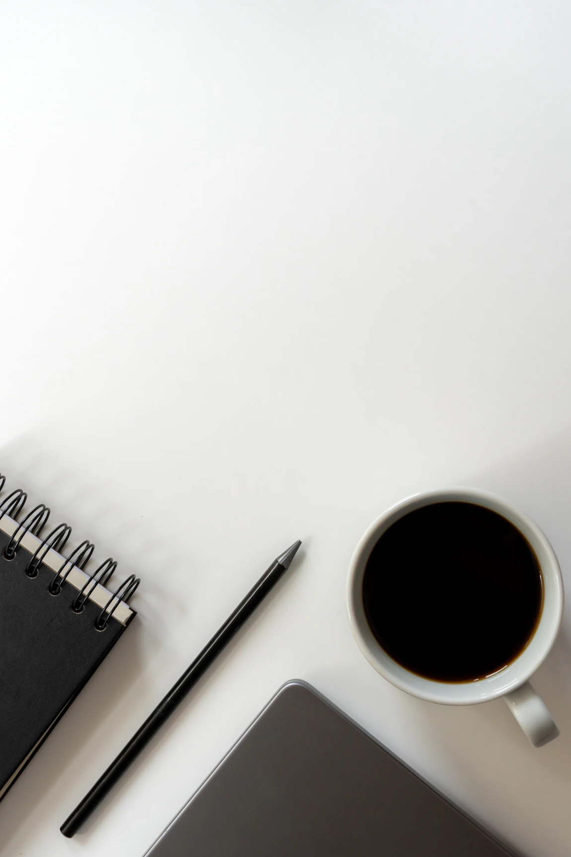 Beeld bij koffie, notitieboek en laptop op een lichte werktafel
