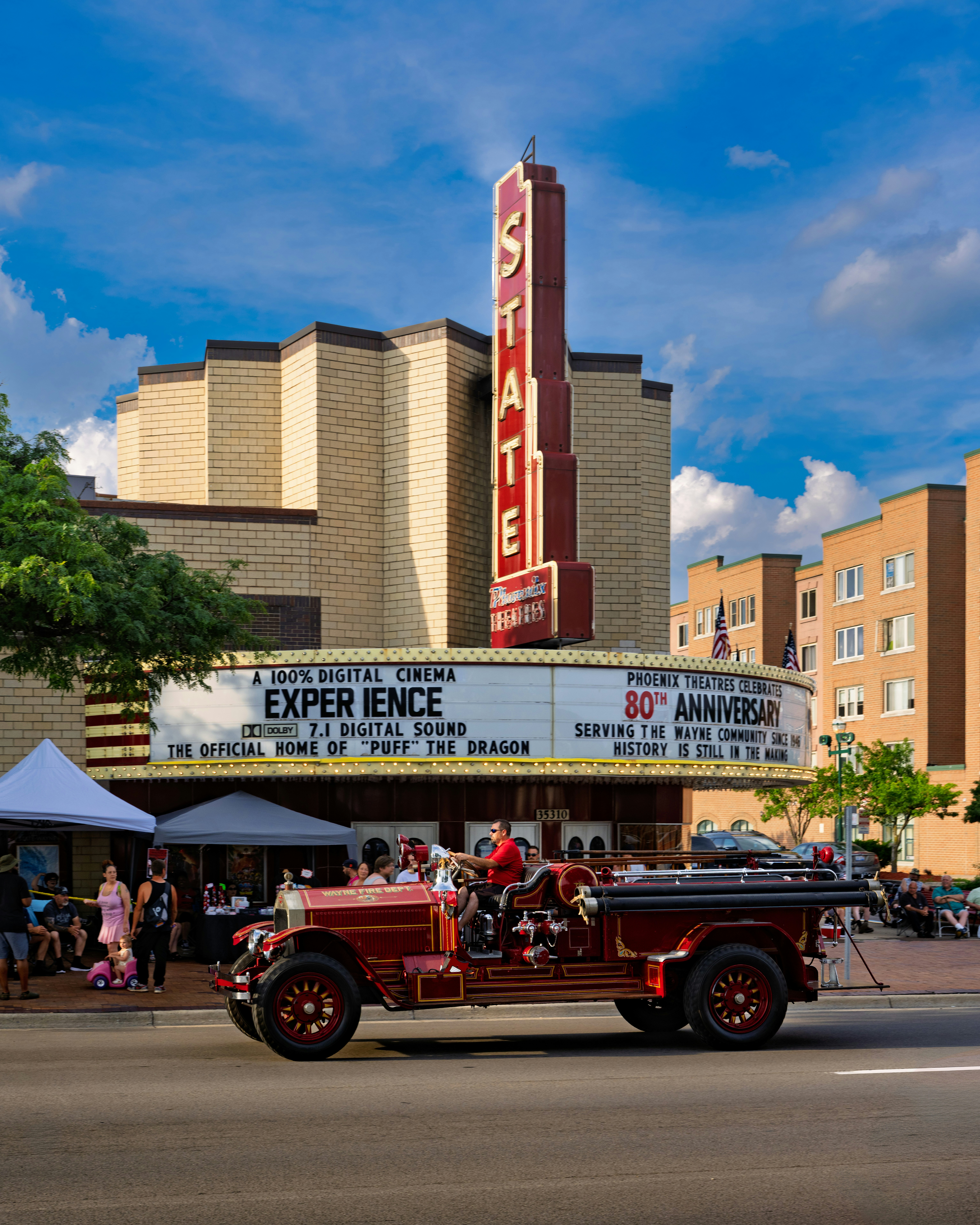 Un camion de pompiers rouge vintage passe devant le théâtre d’État.