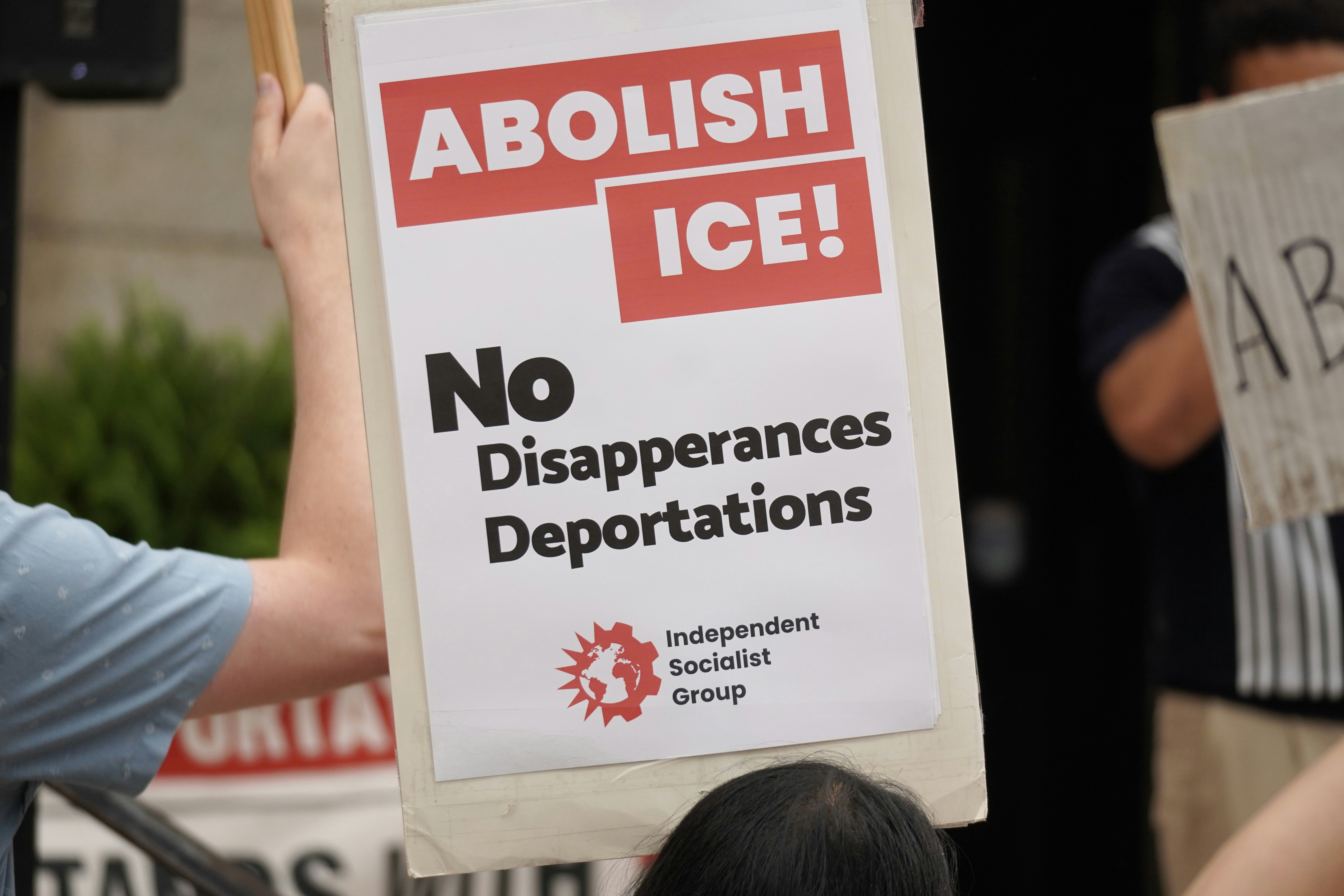 A protest sign says "abolish ice! no disappearances deportations."