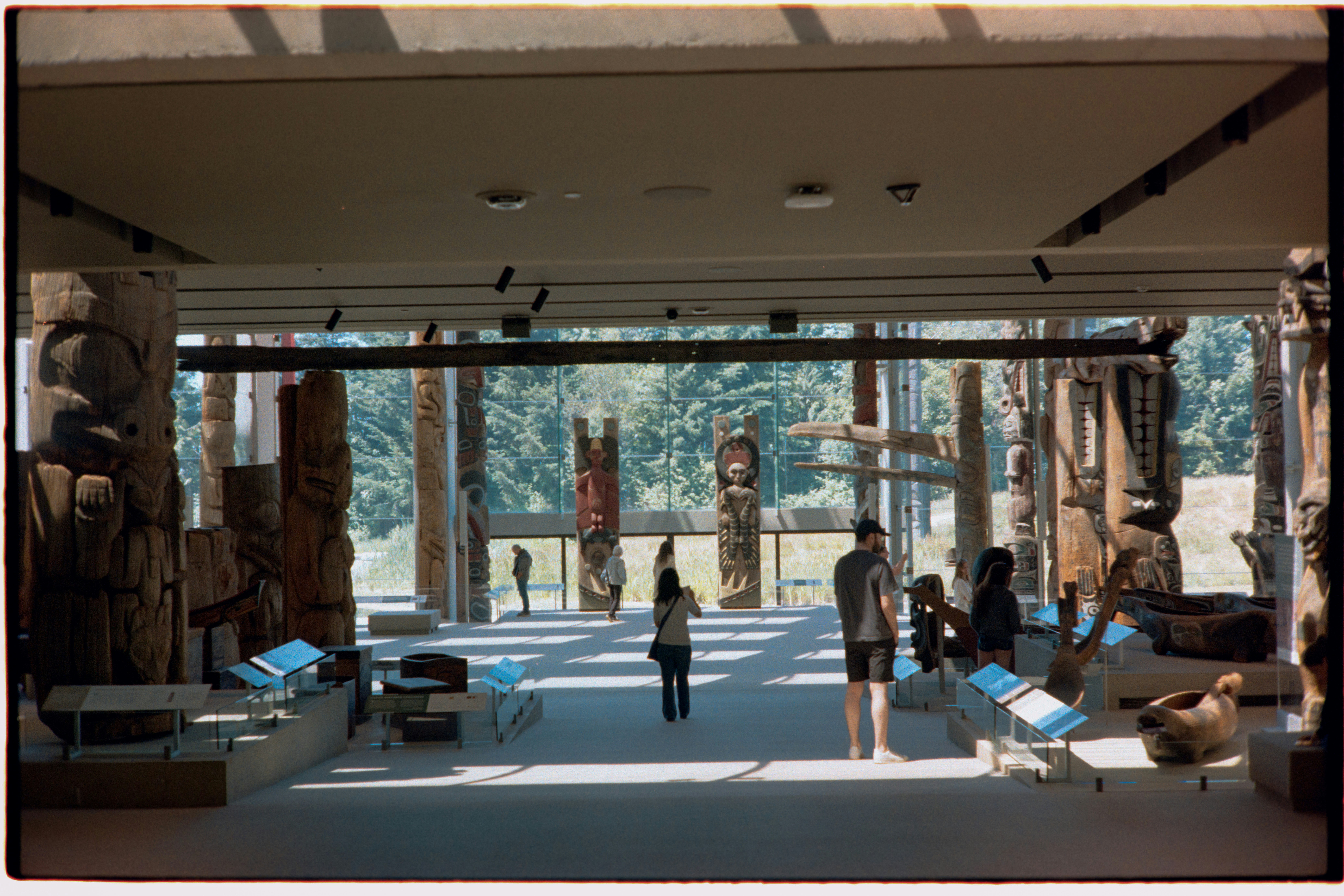 People viewing indigenous totem poles in a spacious museum hall - native american historic sites