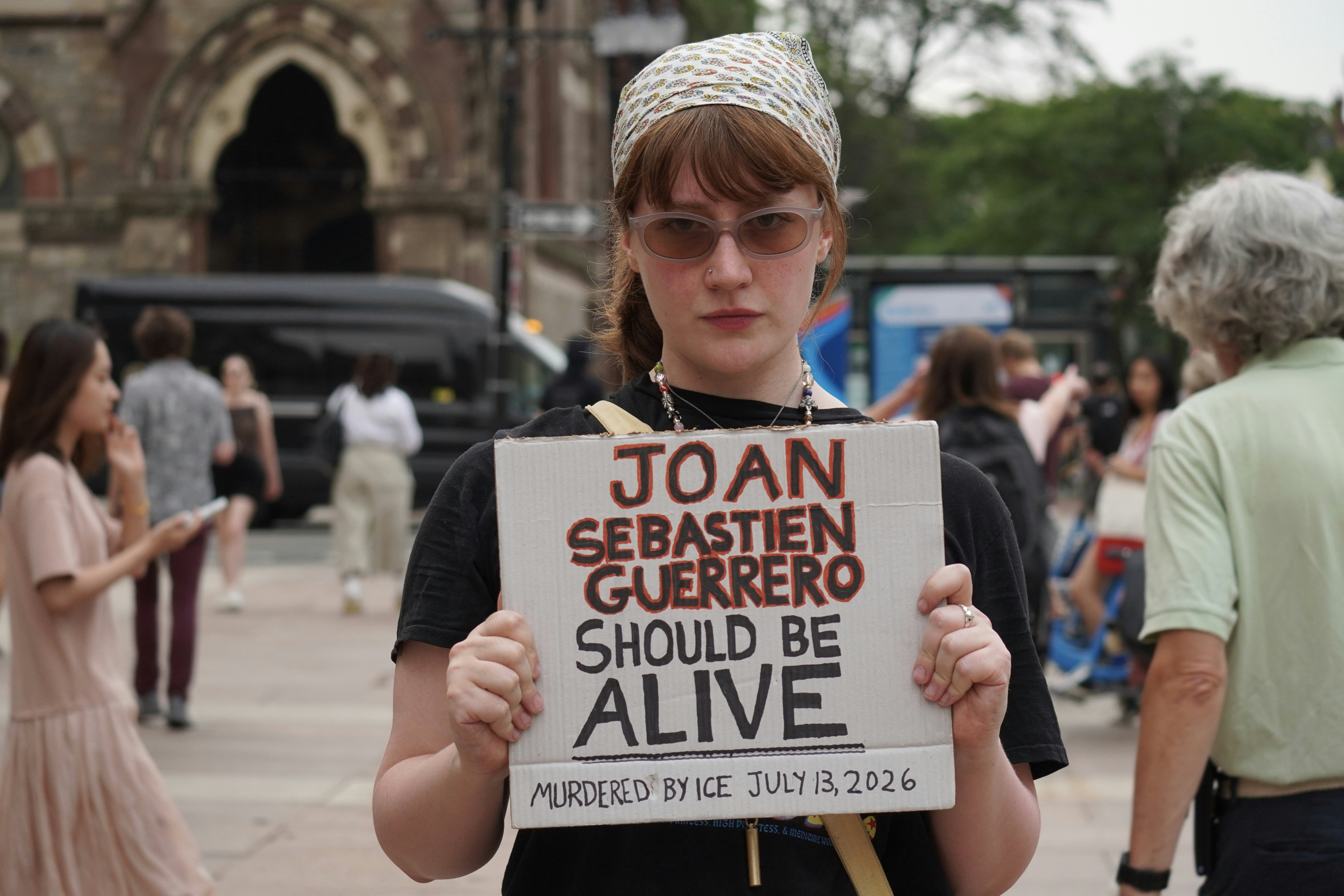Woman holding a sign about joan sebastien guerrero.