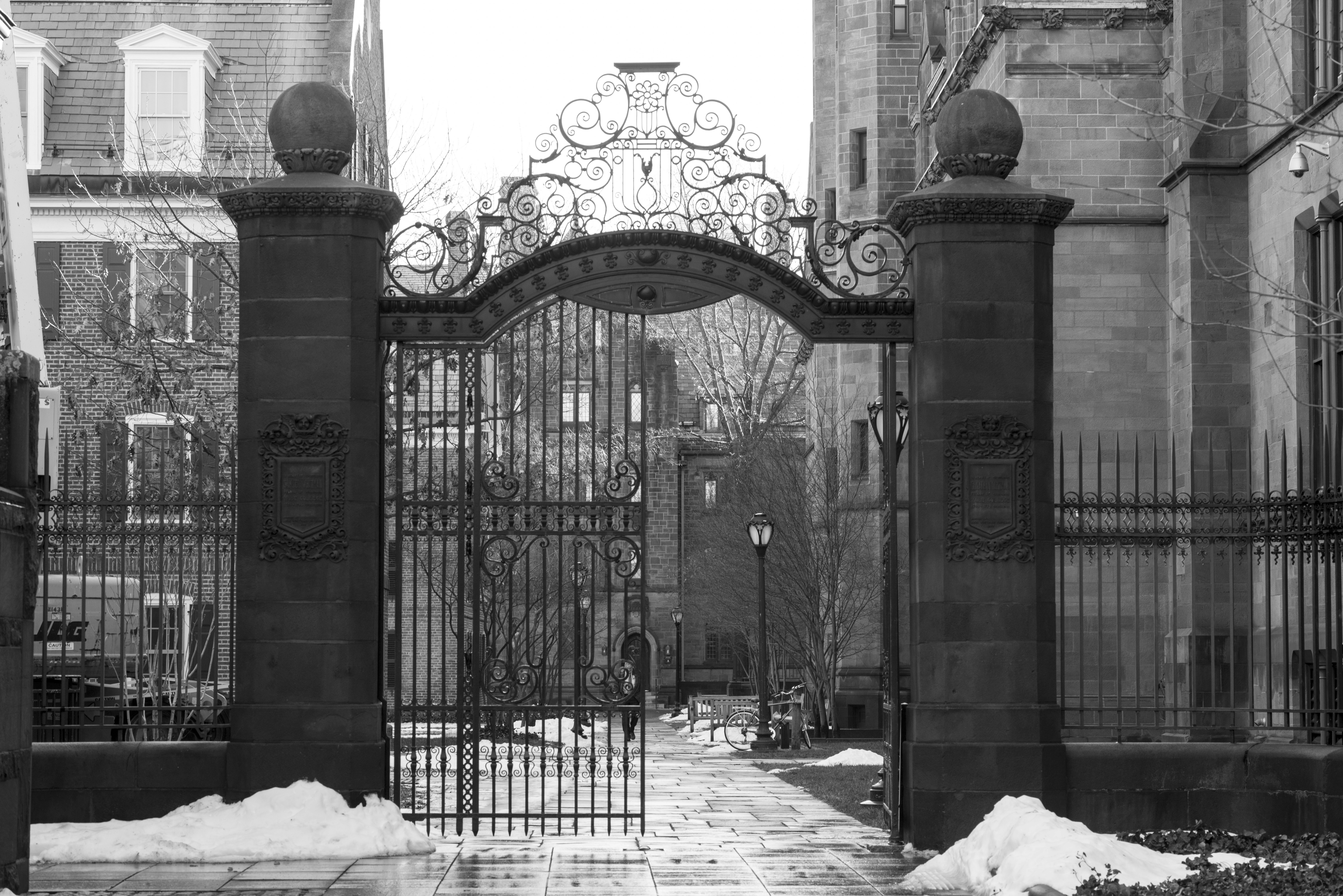 Ornate iron gate framed by pillars with snow