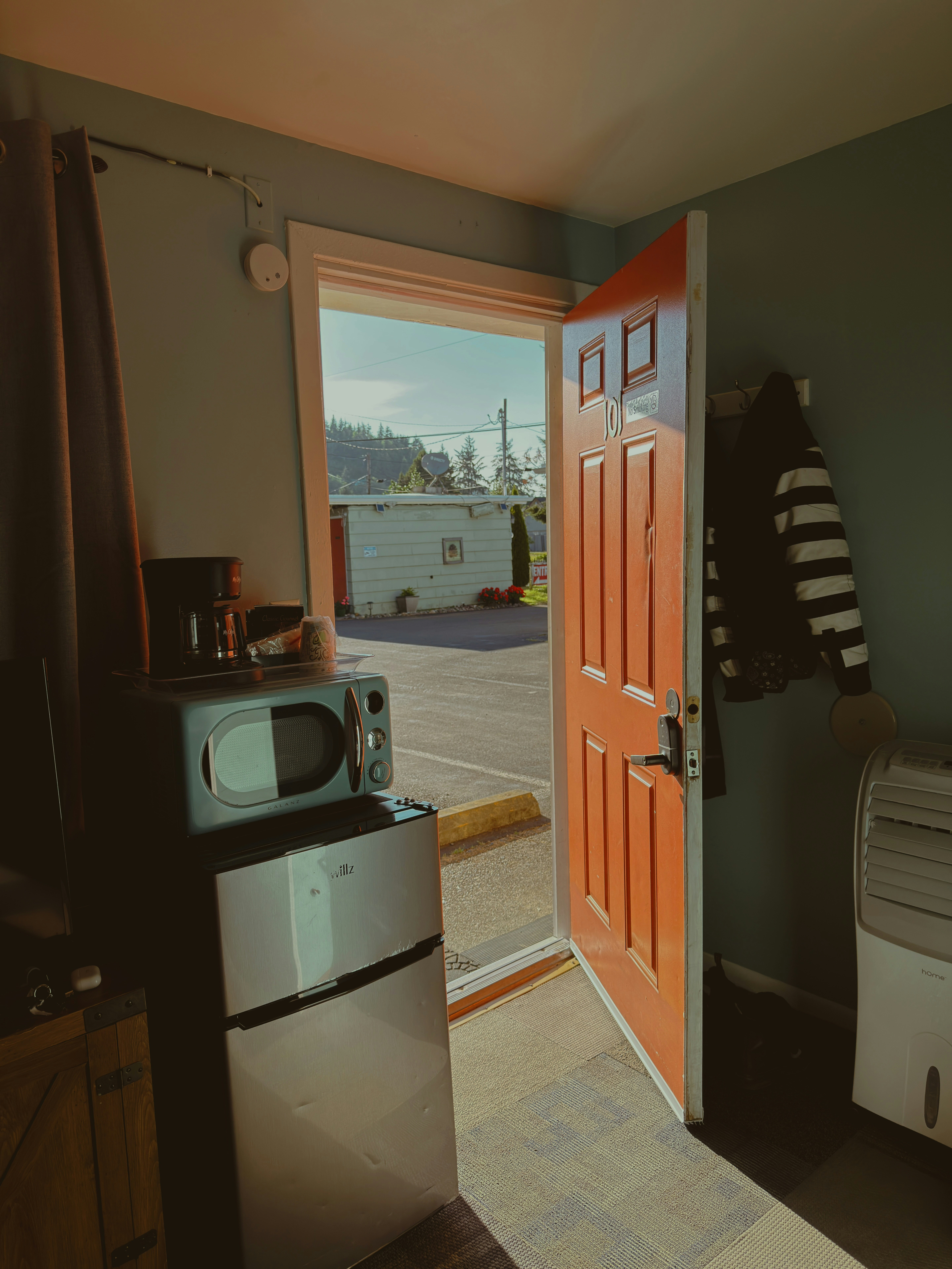 Sunlight streams into a room through an open orange door.