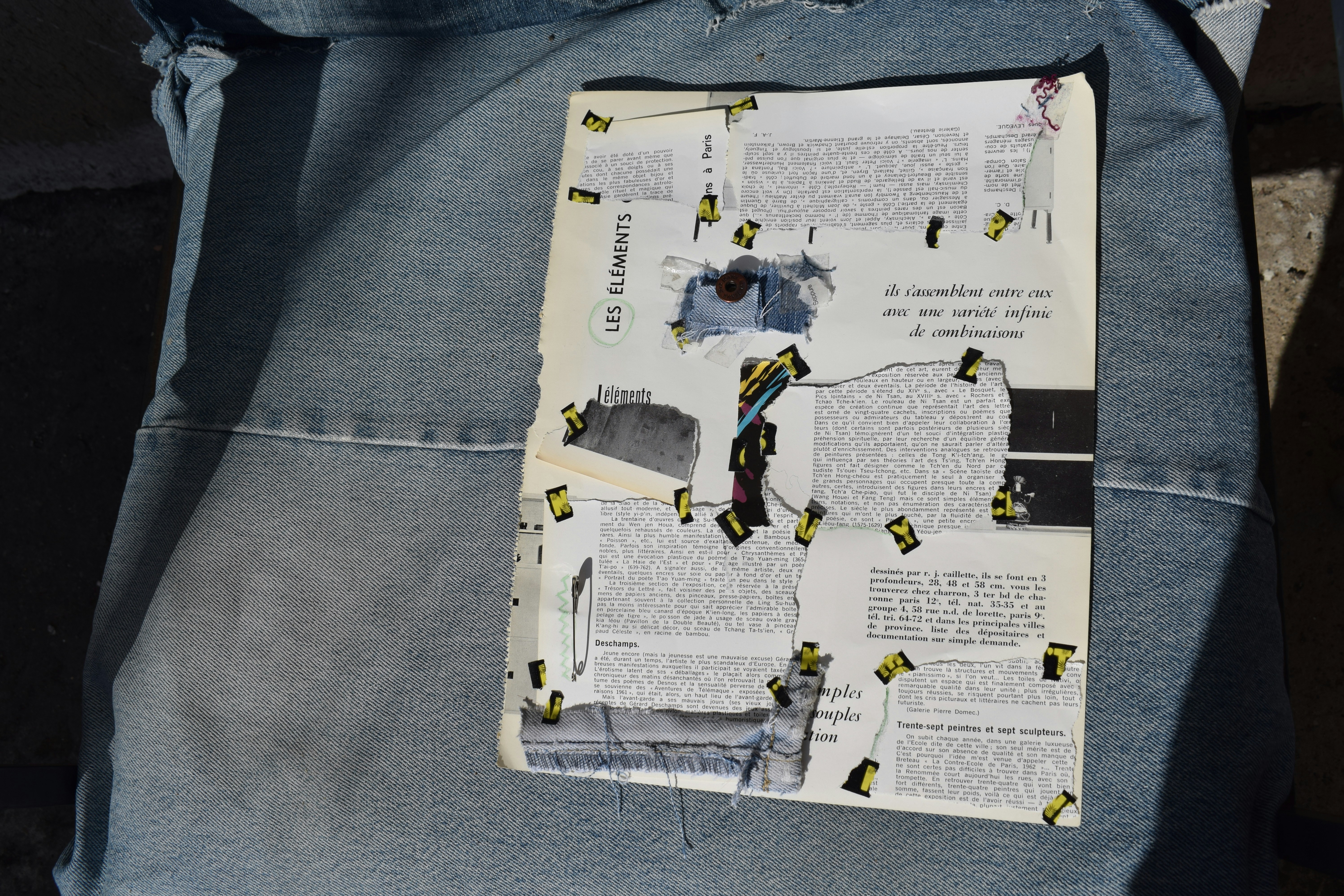 Paper with text and tape pieces on light blue fabric.