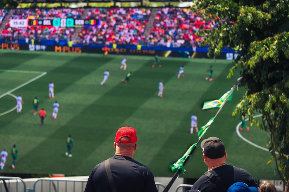 Two spectators watch a soccer game from above the field.