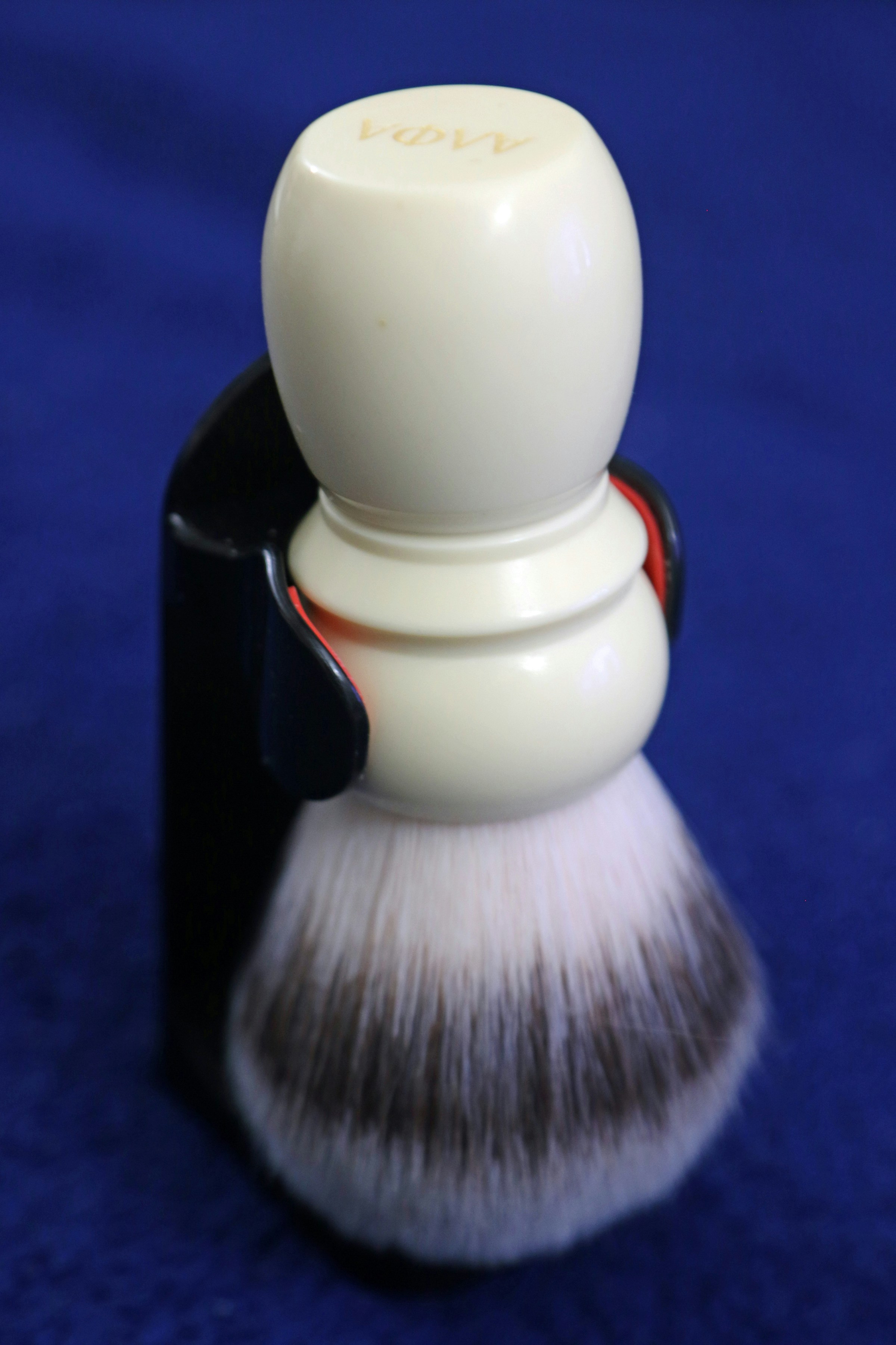 Cream-colored shaving brush with dark and light bristles.
