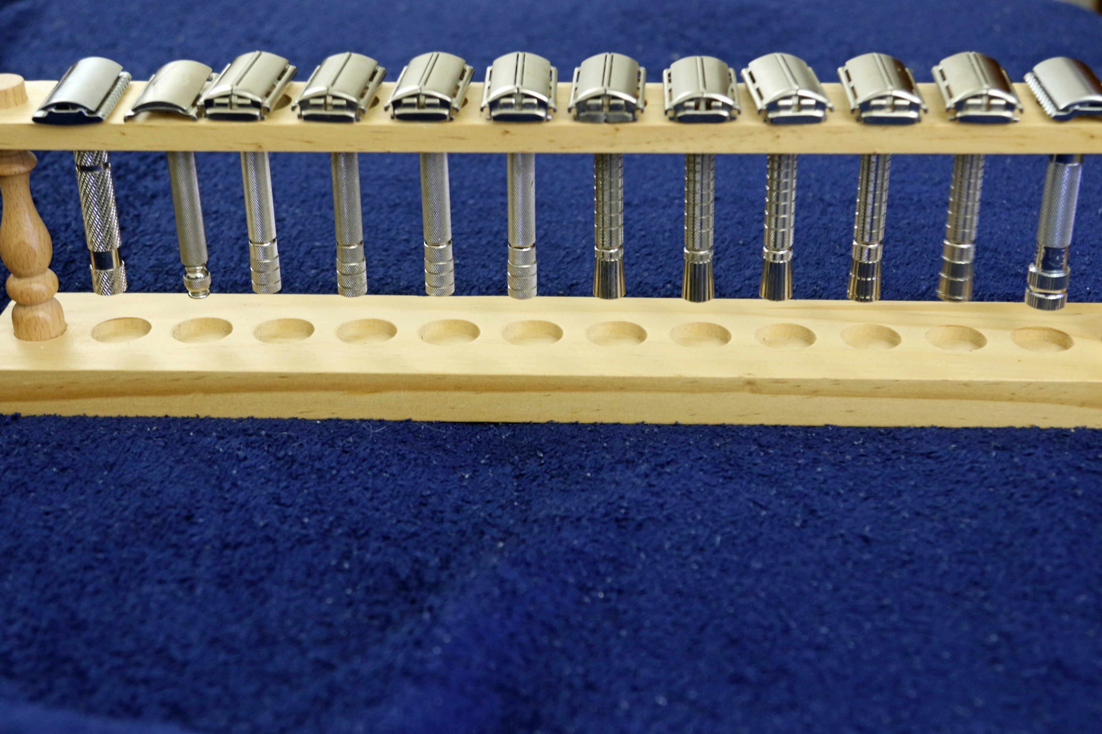 Metal safety razors organized in a wooden display stand.