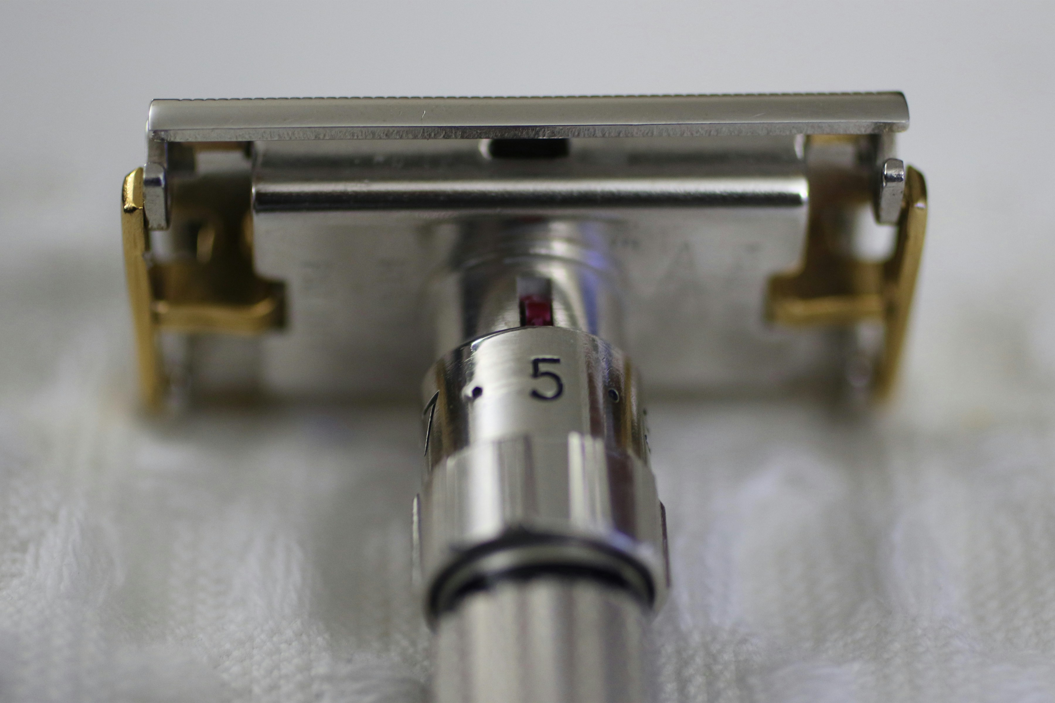 Adjustable safety razor with gold accents on a white surface.